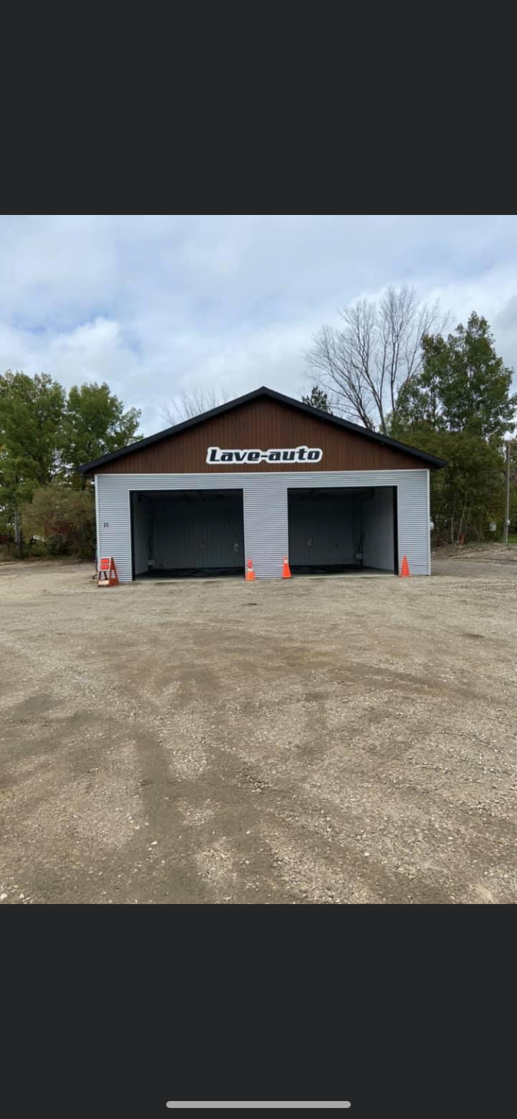 Un garage à deux portes se trouve au milieu d’un champ de terre.