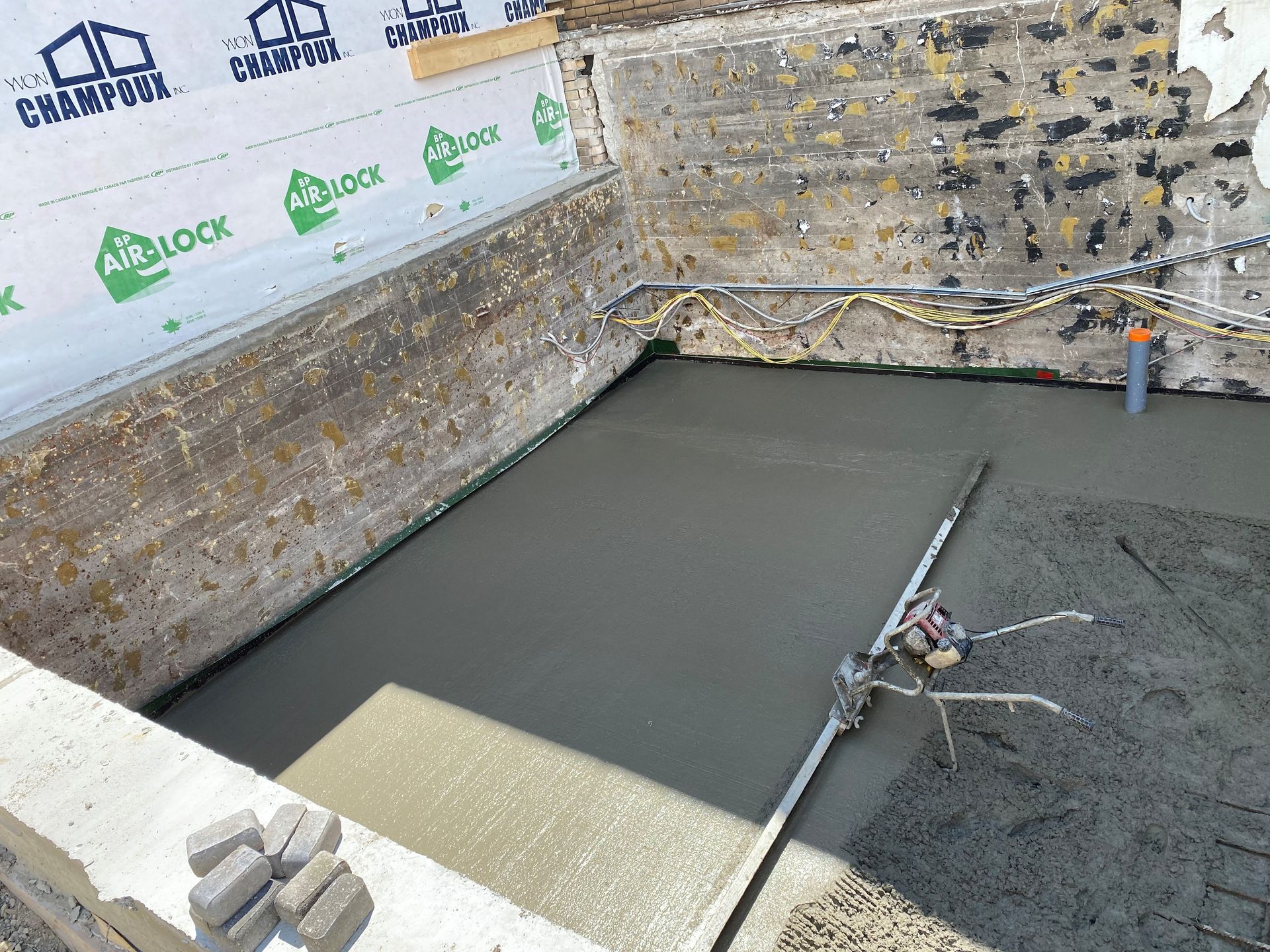 Un sol en béton est en cours de coulée dans un sous-sol en construction.