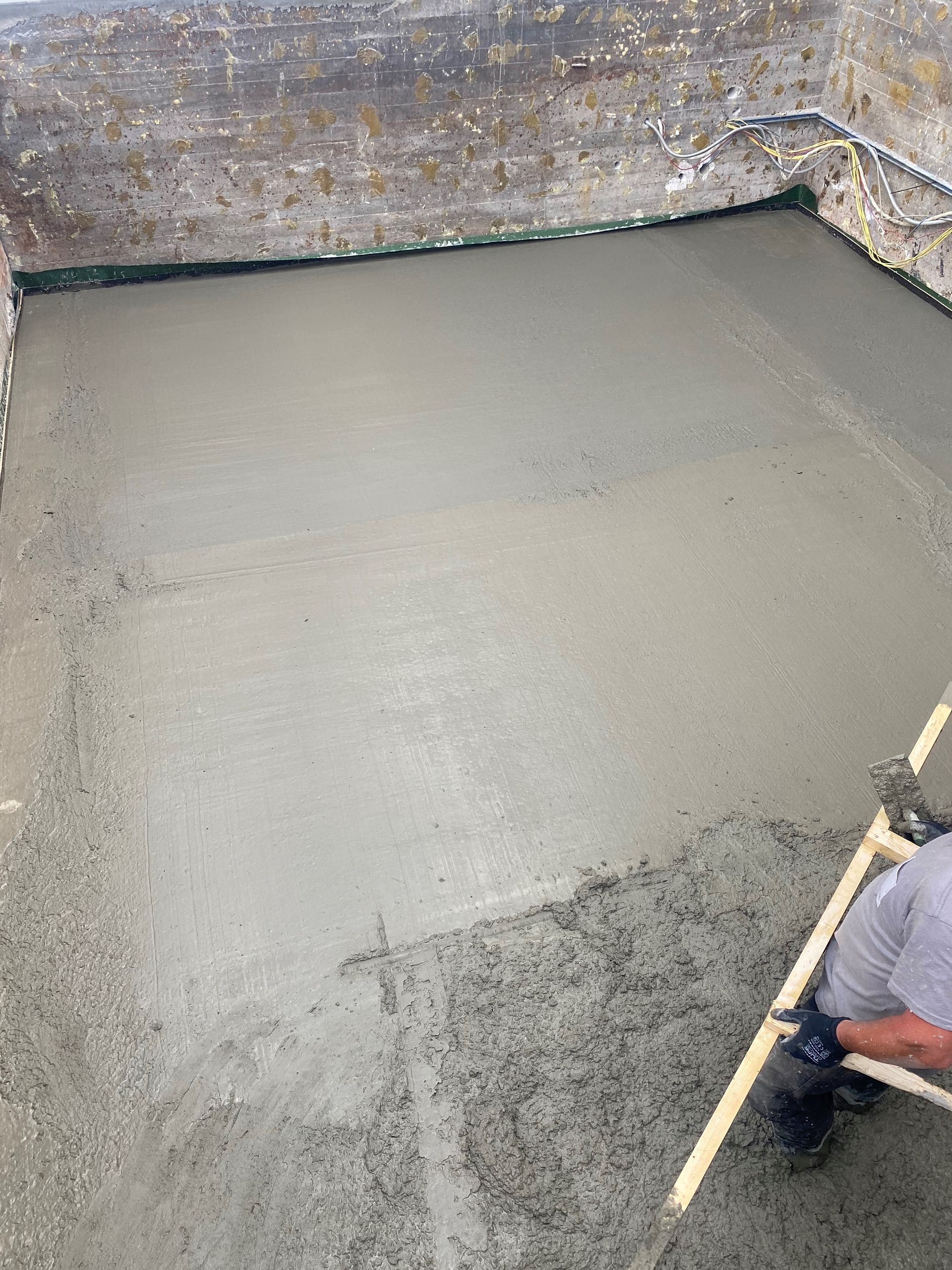 Un homme pose du béton dans un trou avec une pelle.