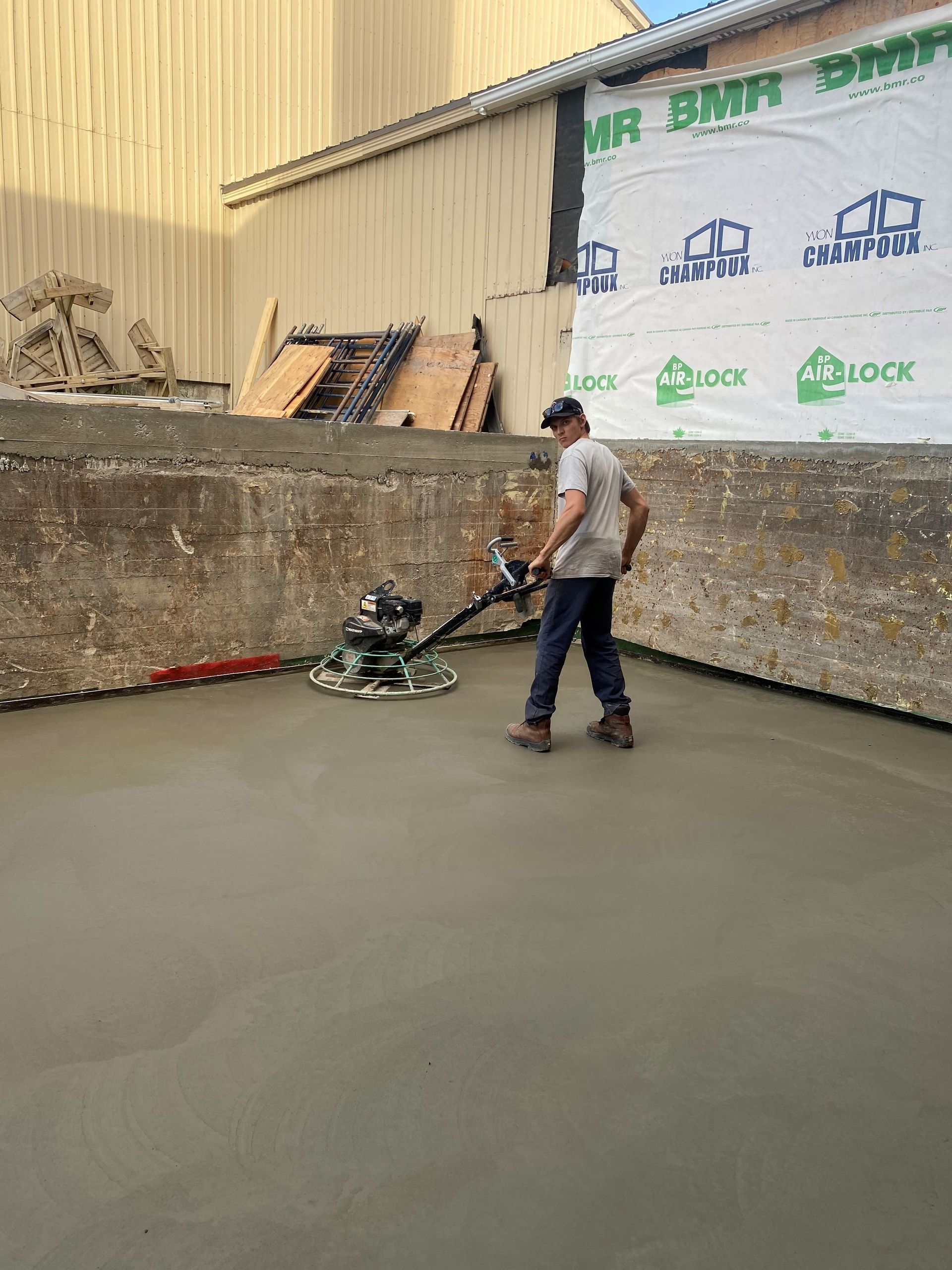 Un homme utilise une machine pour niveler un sol en béton.