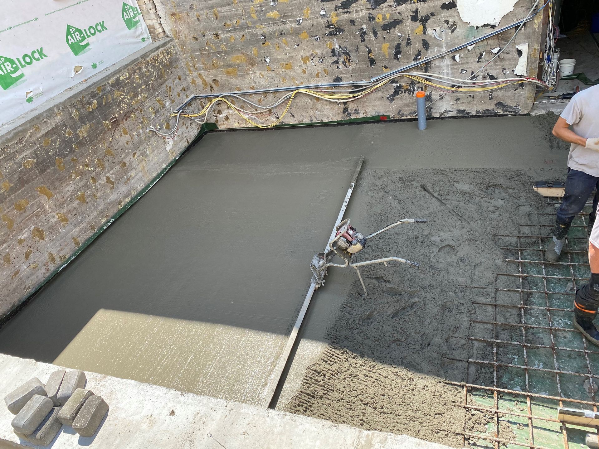 Un homme coule du béton dans un trou creusé dans le sol.