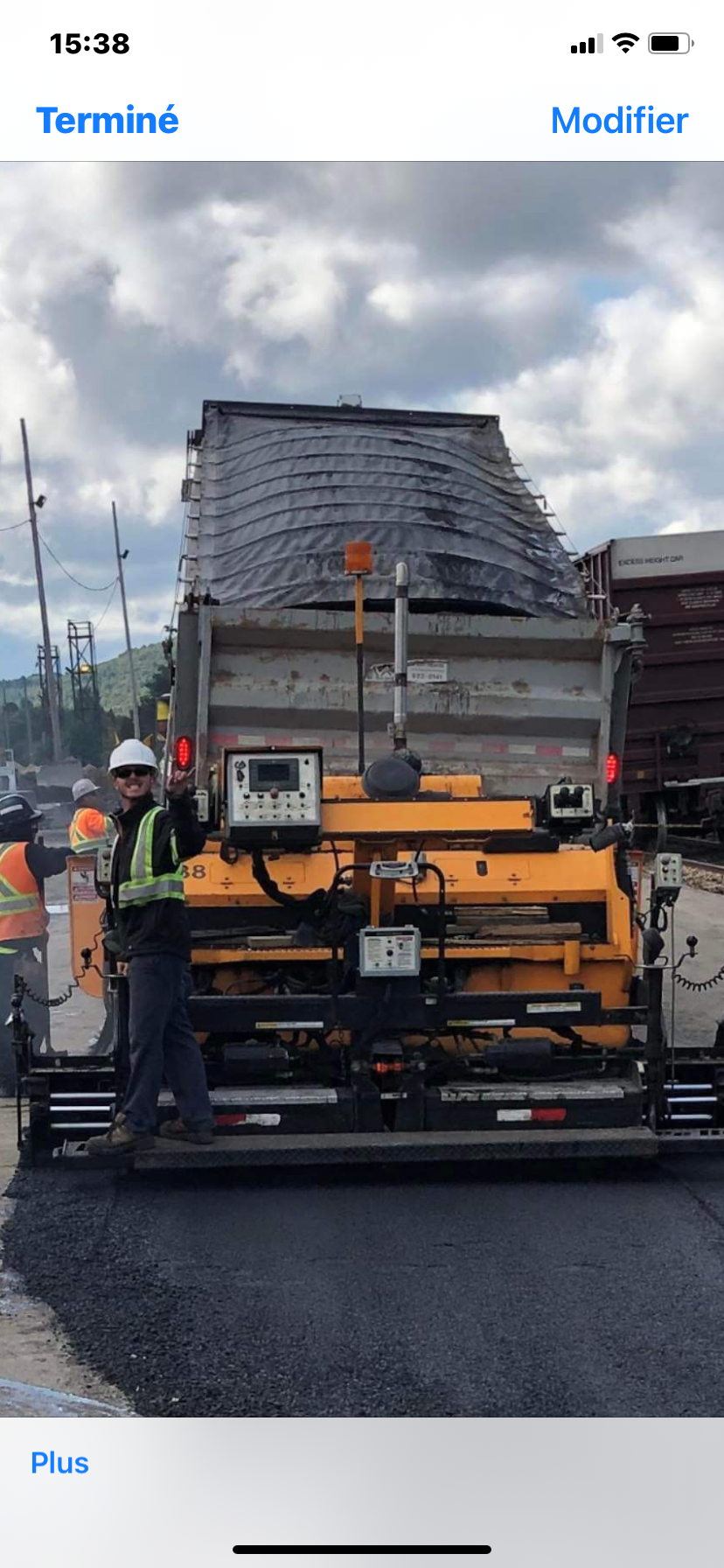 Un homme se tient devant un camion jaune.