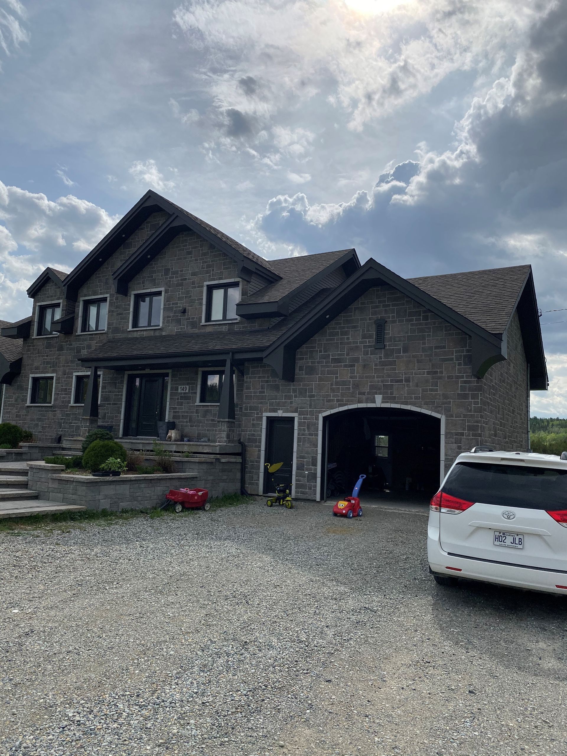 Une grande maison en pierre avec une voiture garée devant.