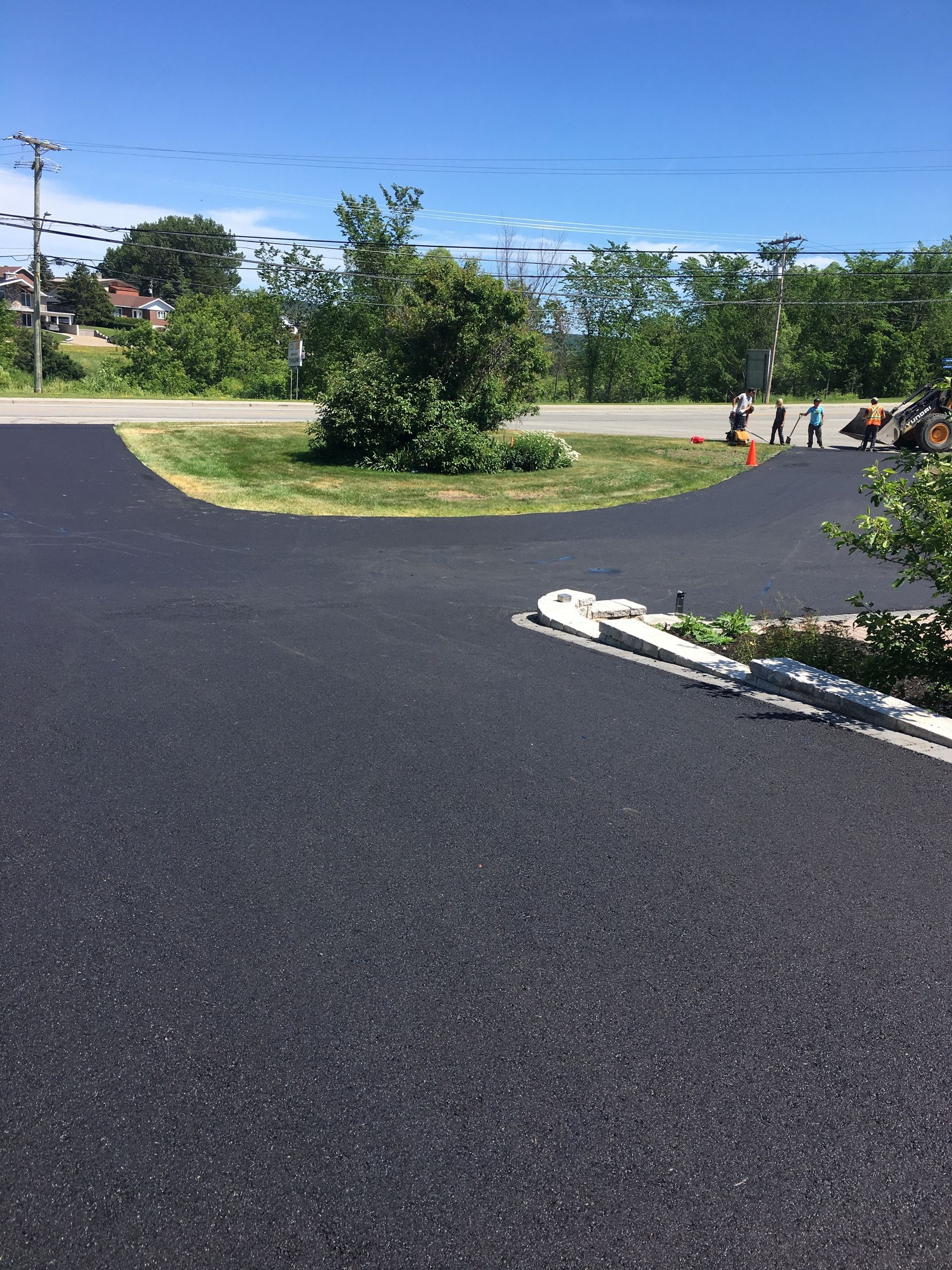 Une route asphaltée noire avec une zone herbeuse au milieu