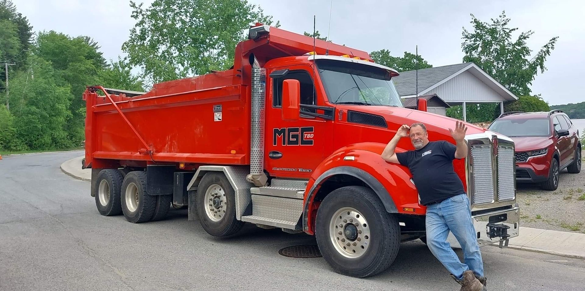 Un homme se tient devant un camion-benne rouge.