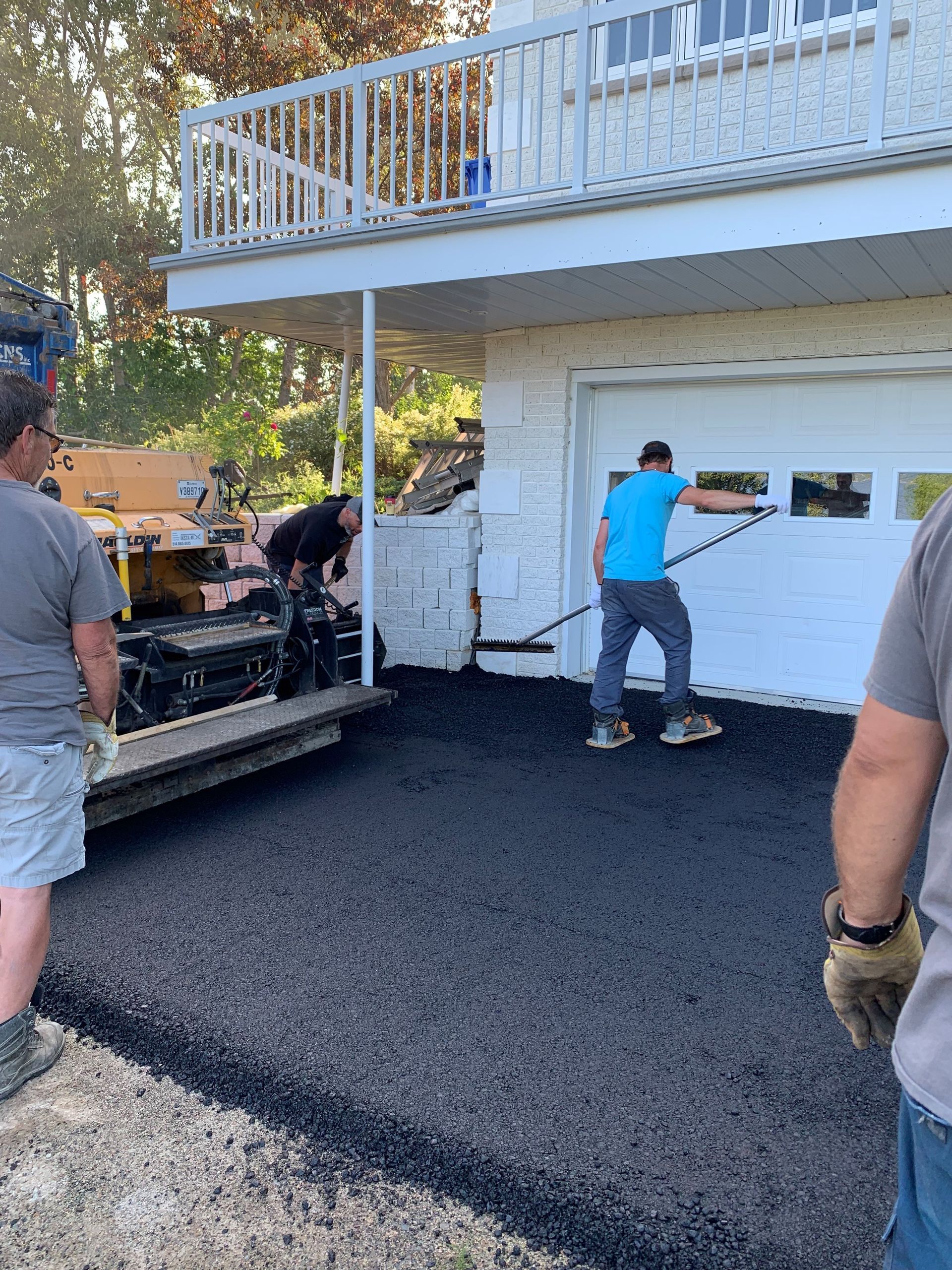 Un groupe d hommes travaille sur une allée devant une maison.