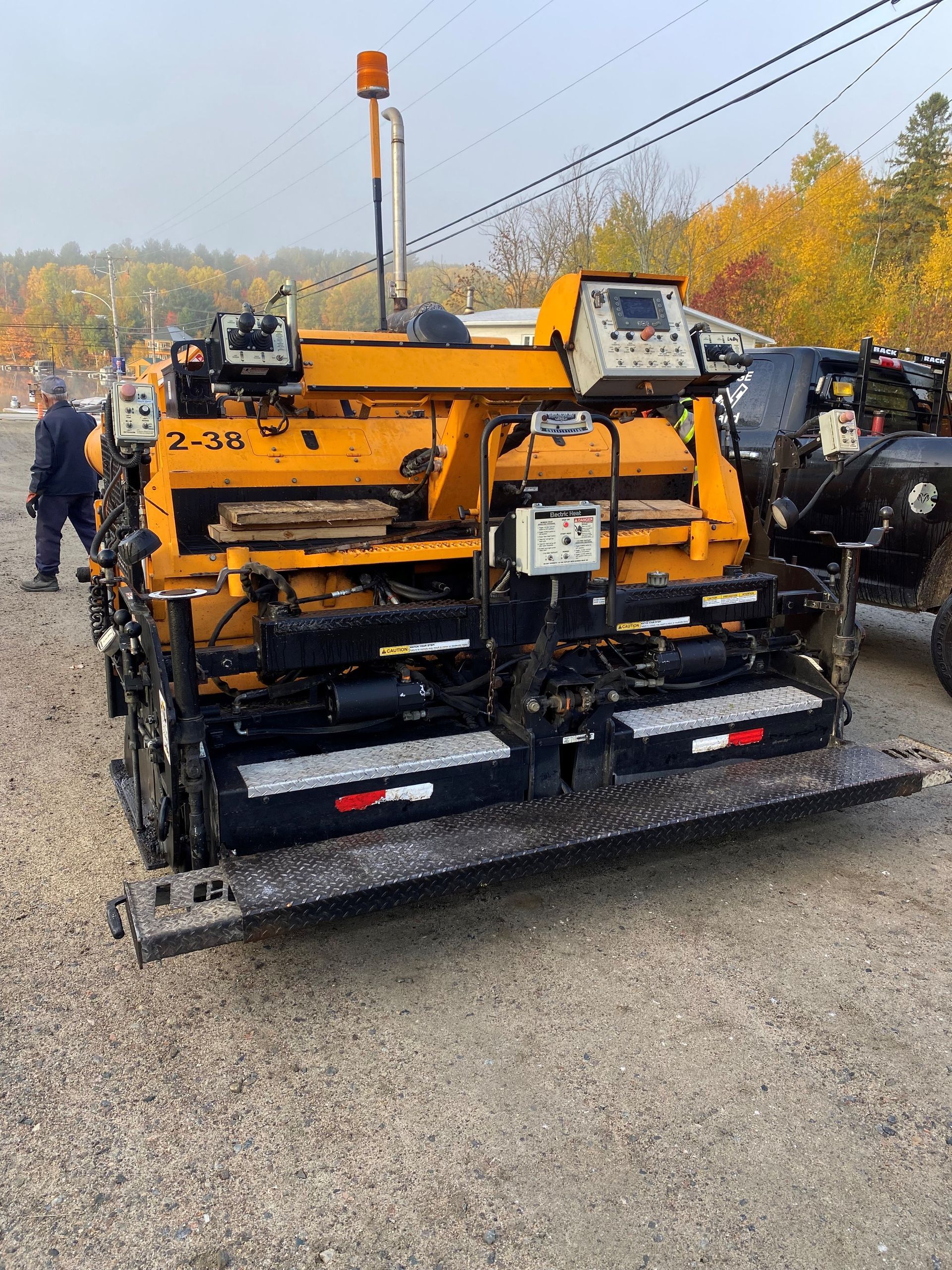 Une machine à asphalter jaune et noire est garée sur une route de gravier.