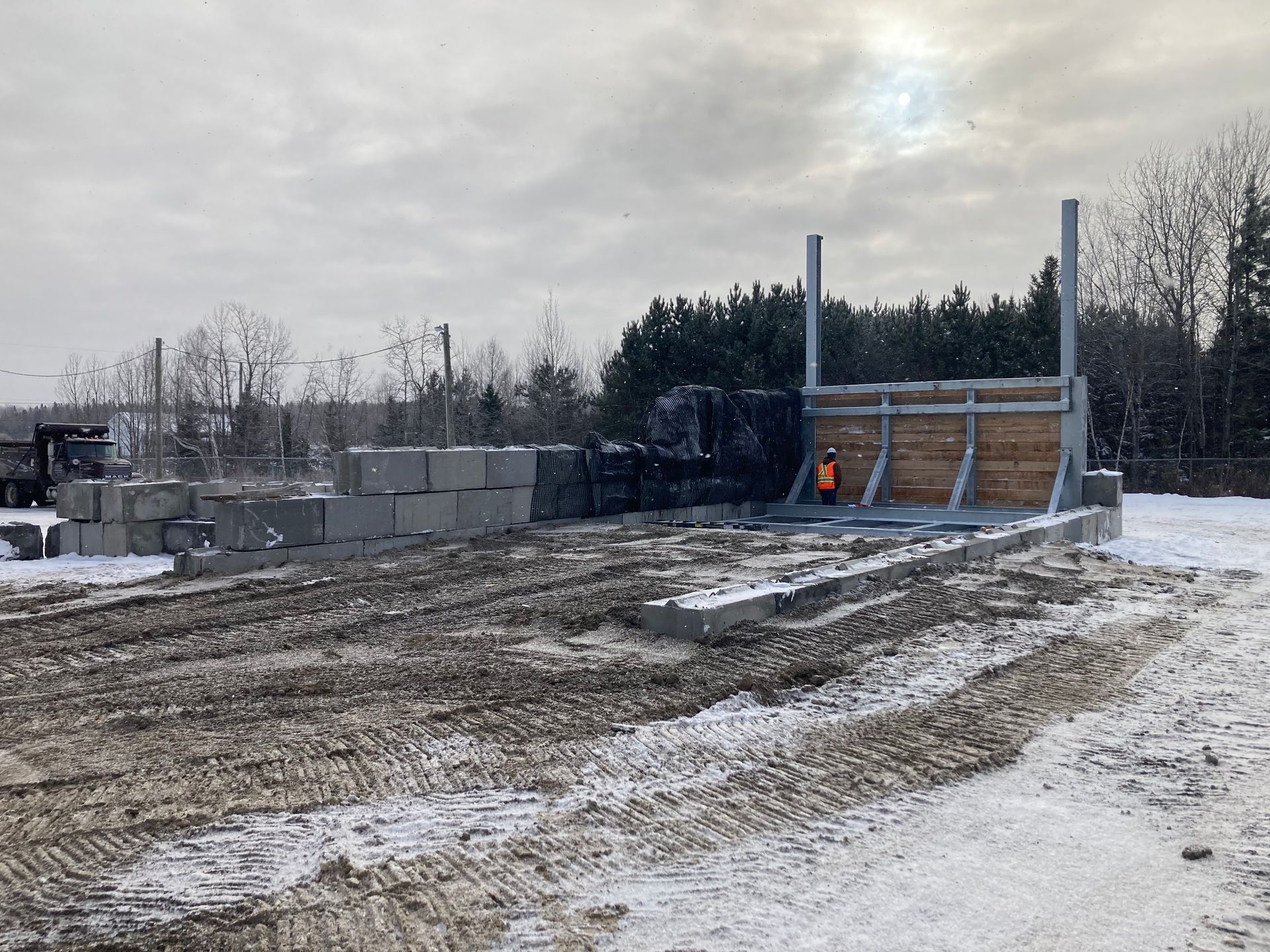 Un homme vêtu d’un gilet orange se tient dans un champ enneigé.