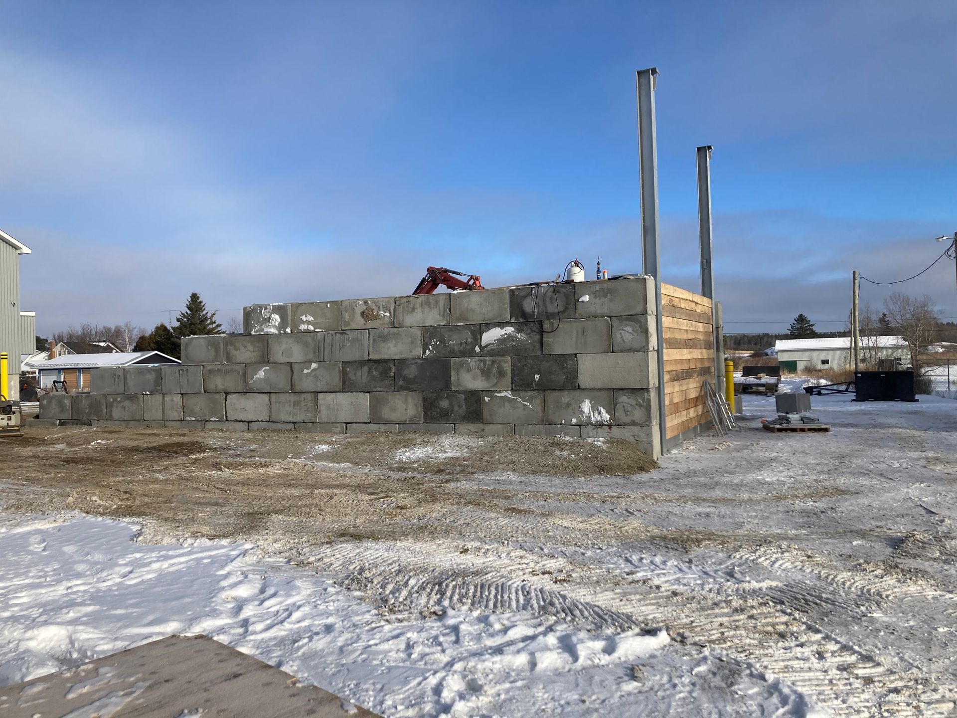 Un grand mur de blocs de béton est en construction dans la neige.
