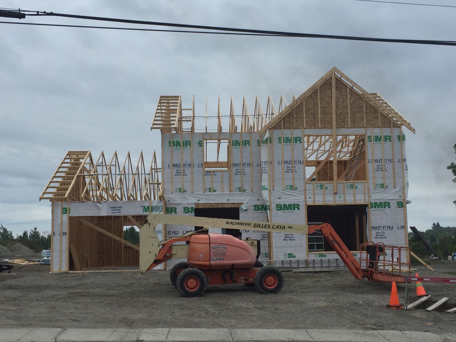 Une maison en construction avec un ascenseur JLG devant