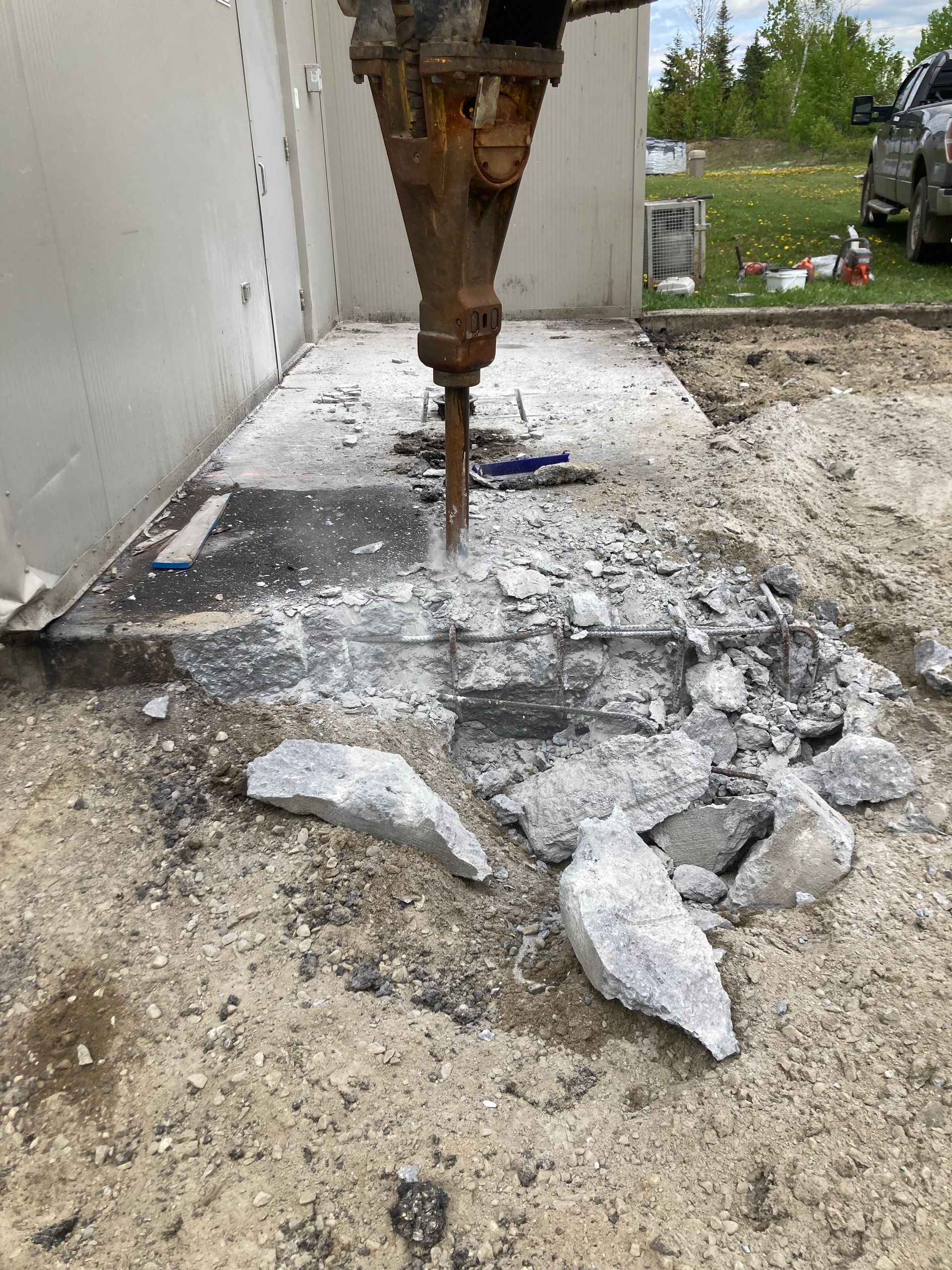 Un brise-béton brise le béton au sol.