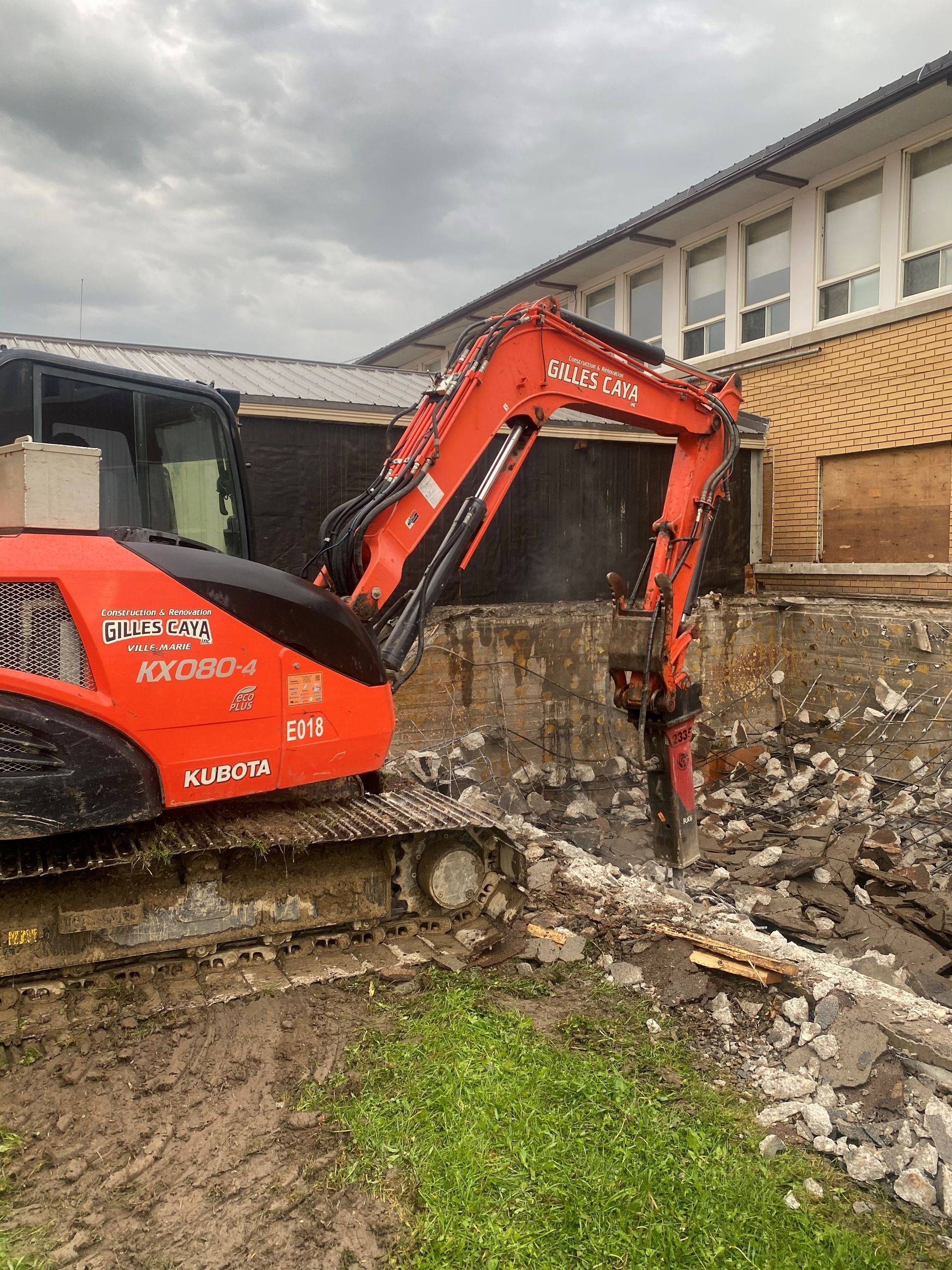 Une grande excavatrice orange est en train de démolir un bâtiment.