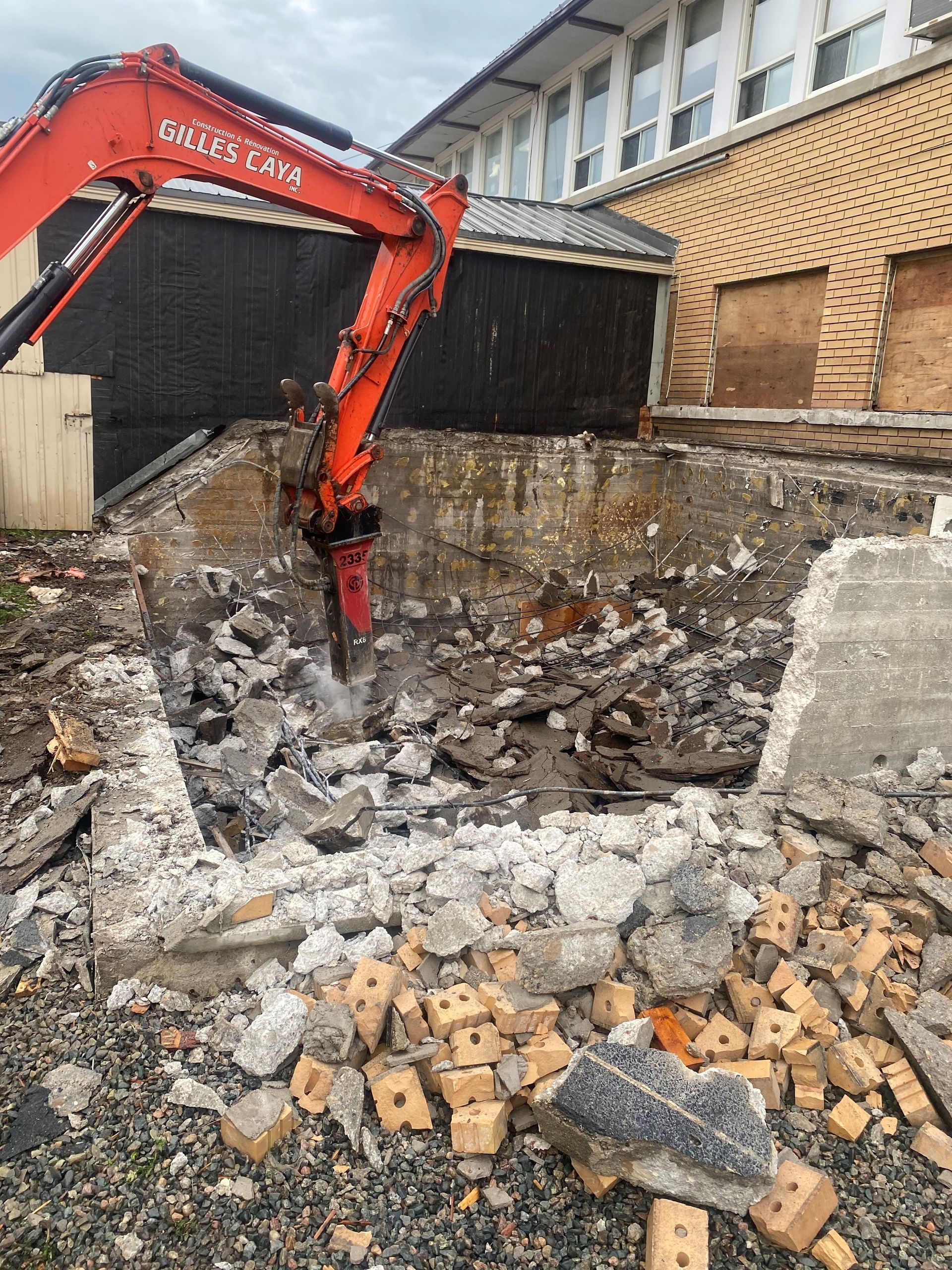 Une grande excavatrice orange est en train de démolir un bâtiment.