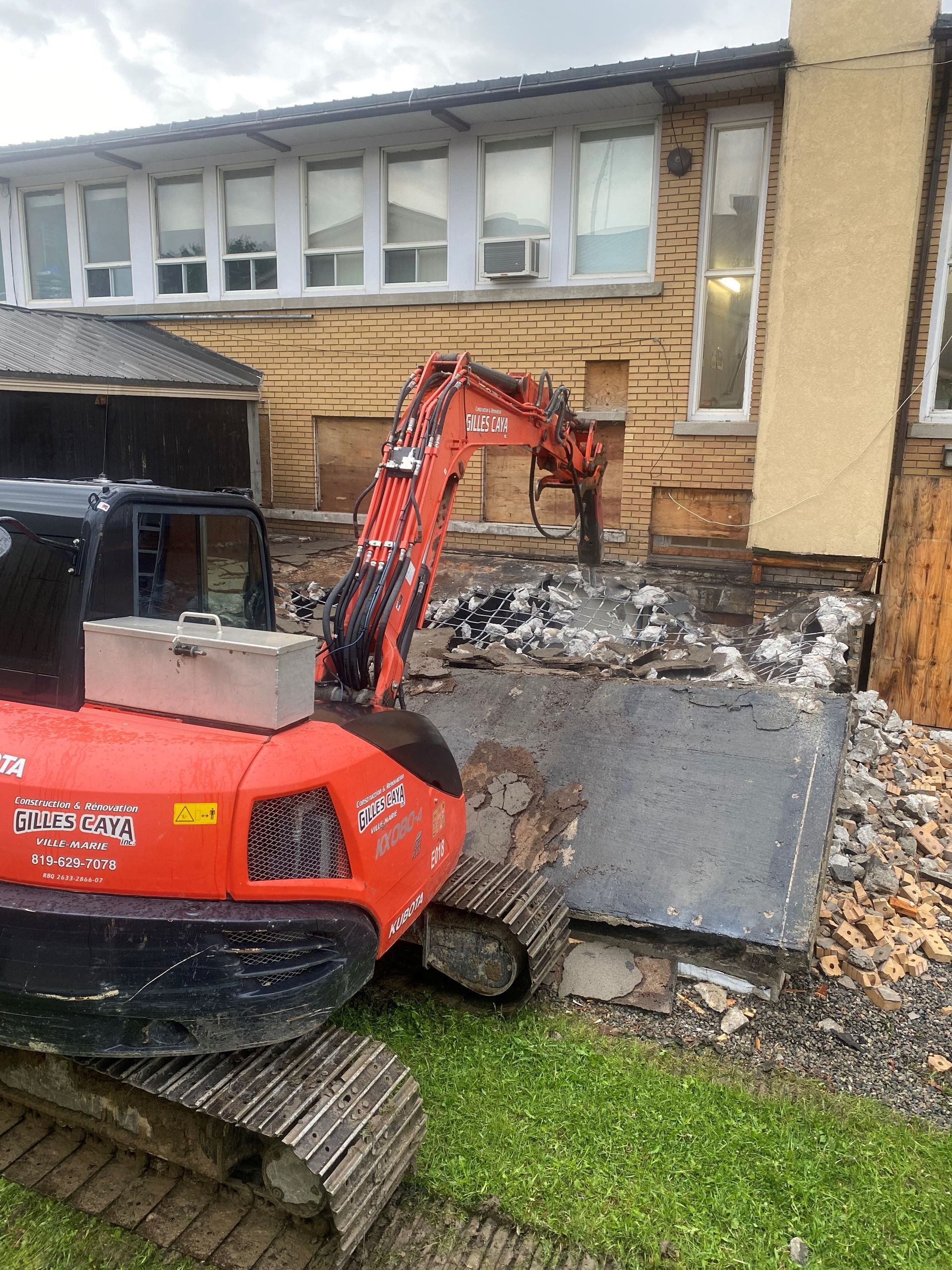 Une excavatrice orange est utilisée pour démolir un bâtiment.