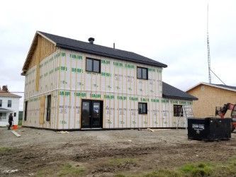 Une maison est en construction au milieu d’un champ de terre.