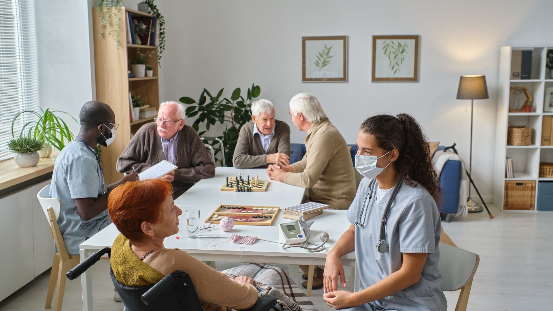 Group of seniors and nurses in a room, playing games and socializing.