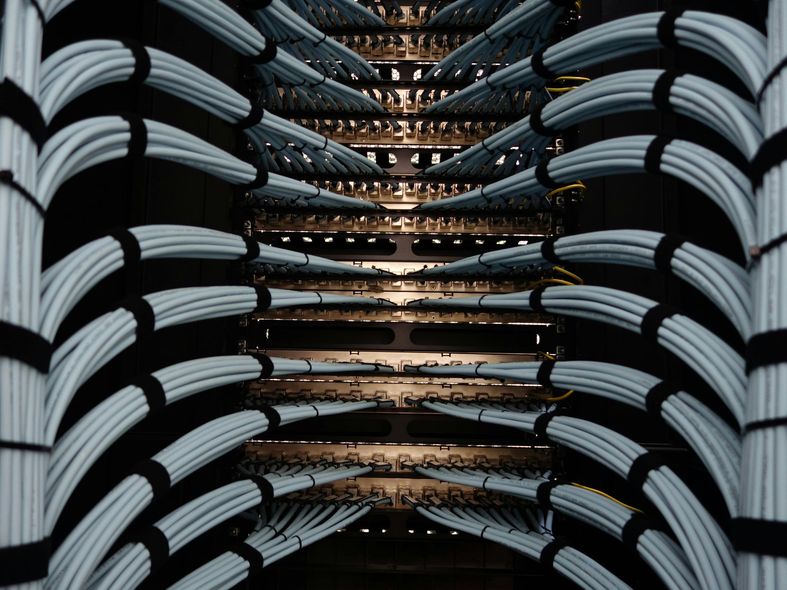 Data center with numerous neatly organized network cables, bundled and secured.
