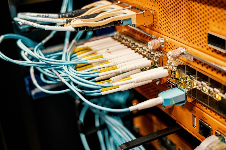 Orange server rack with multiple blue fiber optic cables connected.