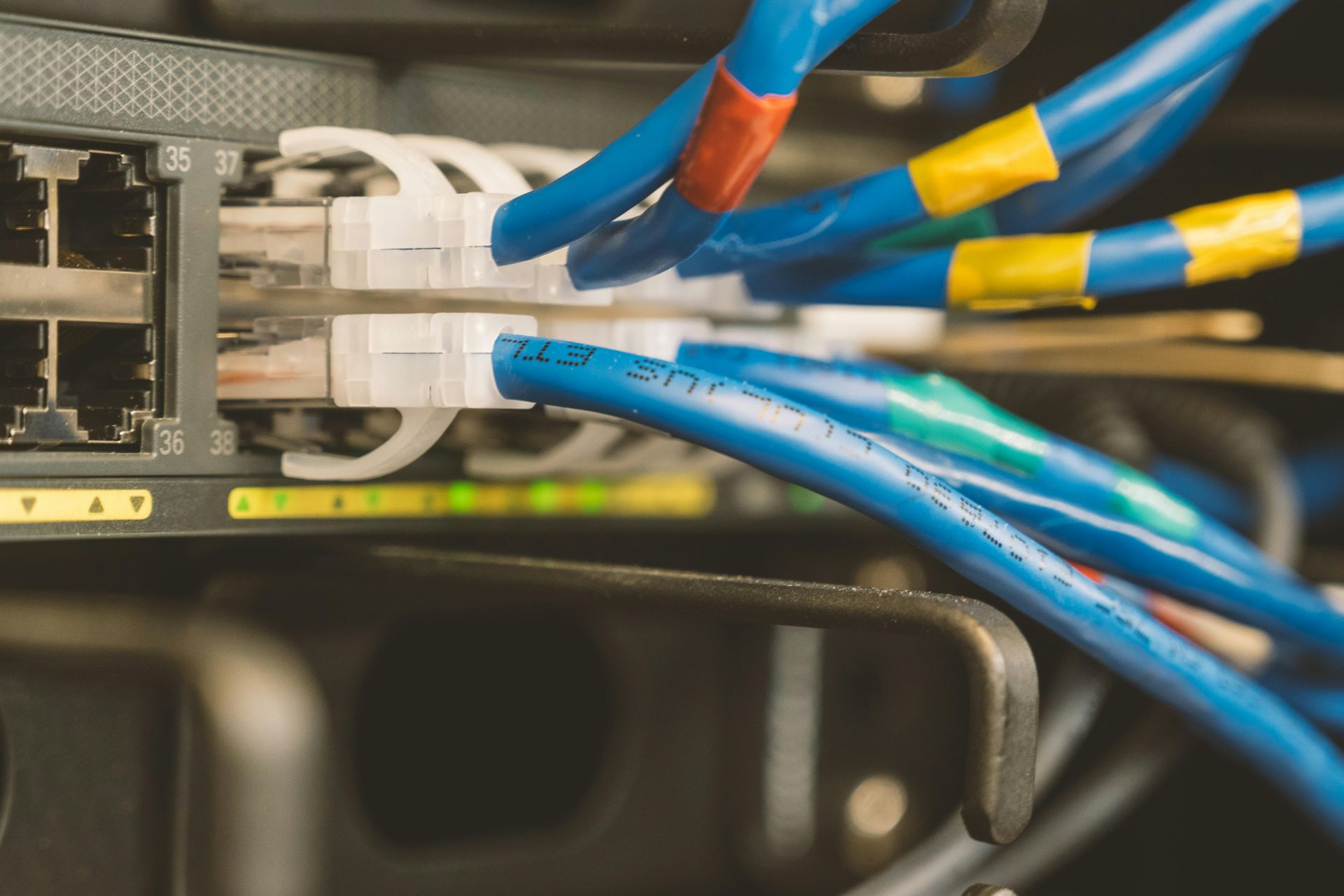 Network switch with blue Ethernet cables plugged in; various colored labels visible.