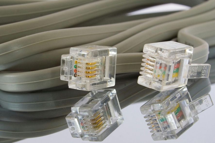 Two clear telephone connectors with gold contacts and grey cable.