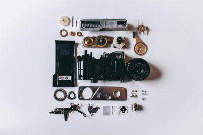 Disassembled camera parts arranged on a white surface, top-down view.