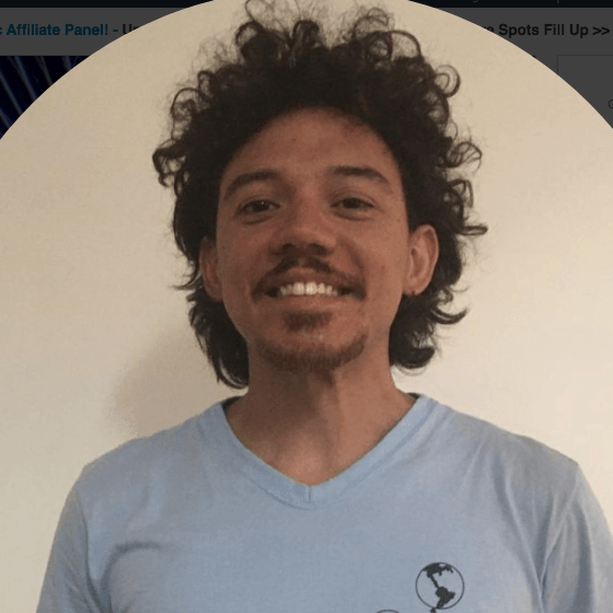 Um homem com cabelos cacheados e barba vestindo uma camisa azul