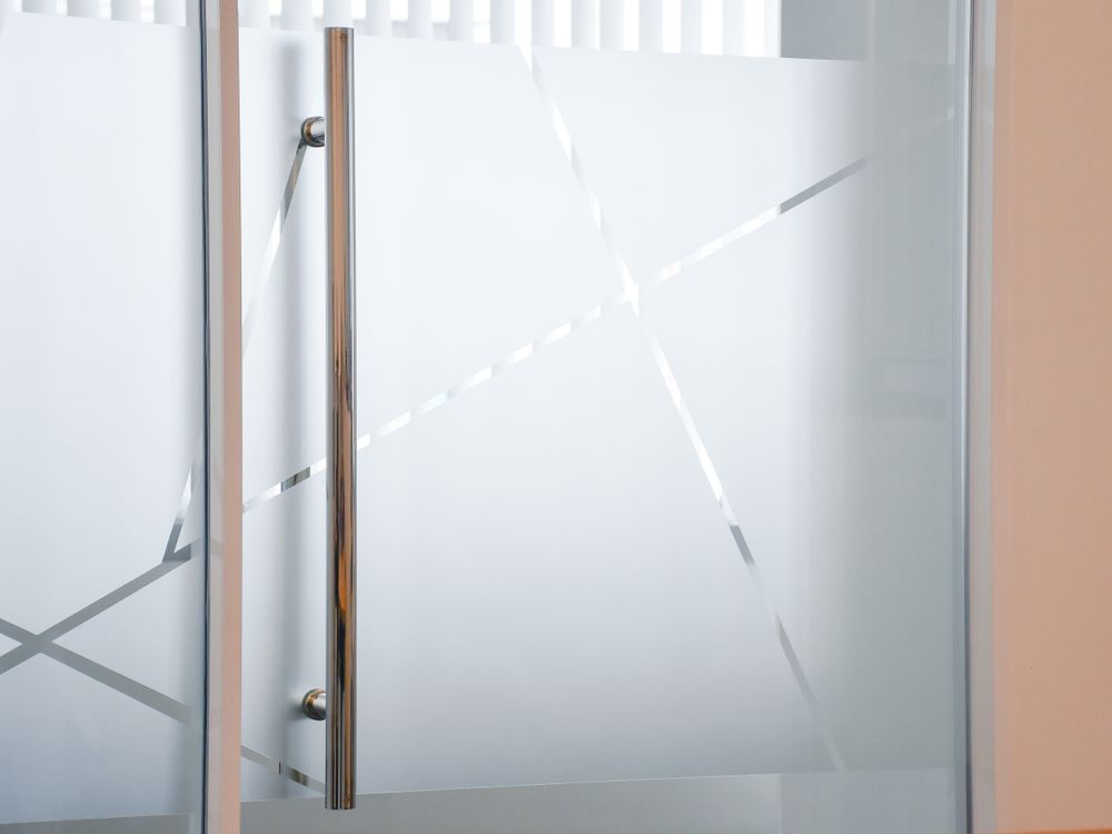 A Frosted Glass Door with Geometric Design and Metal Handle — Downs Window Renewals in Harristown, QLD