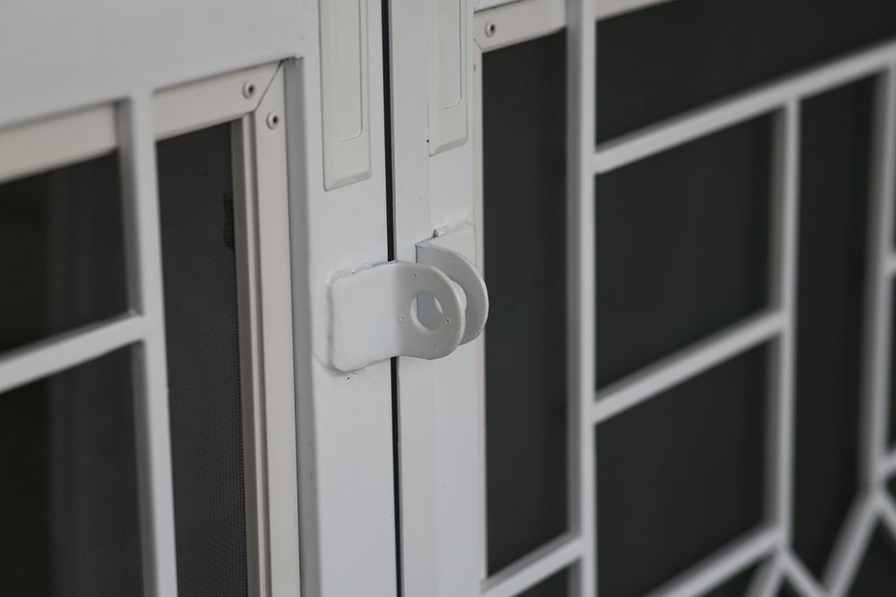 A White Security Door with A Latch and Geometric Grid Pattern — Downs Window Renewals in Harristown, QLD