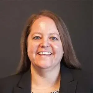 A woman in a black jacket is smiling for the camera.