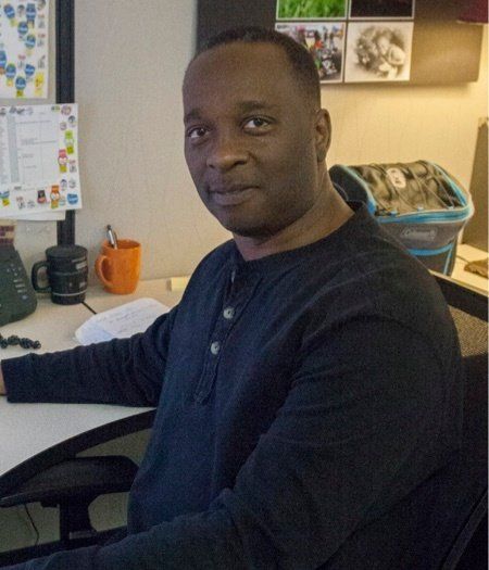 A man in a black shirt is sitting at a desk