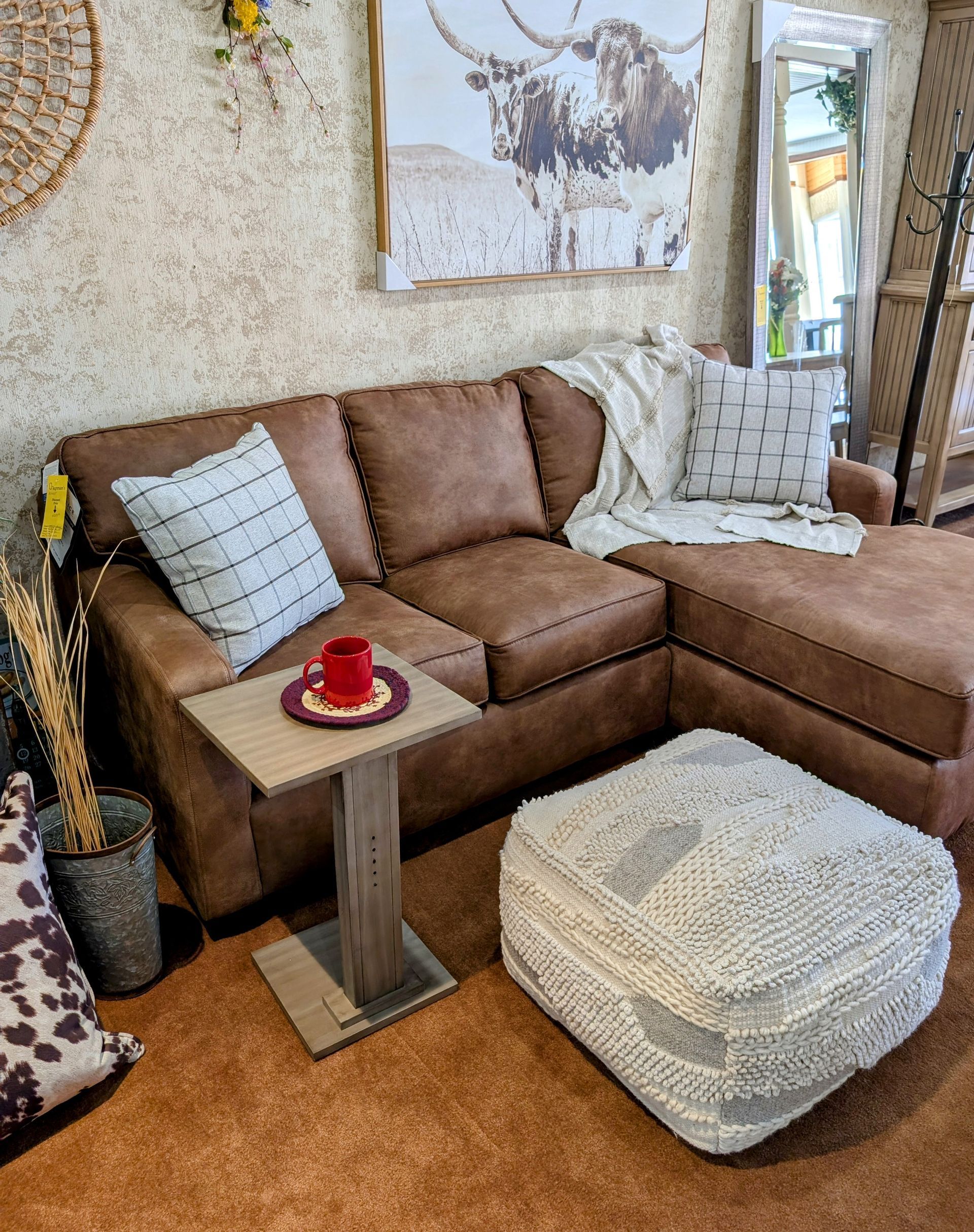 A living room with a couch , ottoman , coffee table and a painting on the wall.
