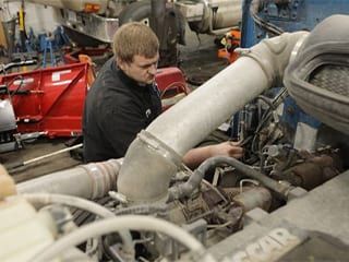 Mechanic working on a truck engine in a repair shop.