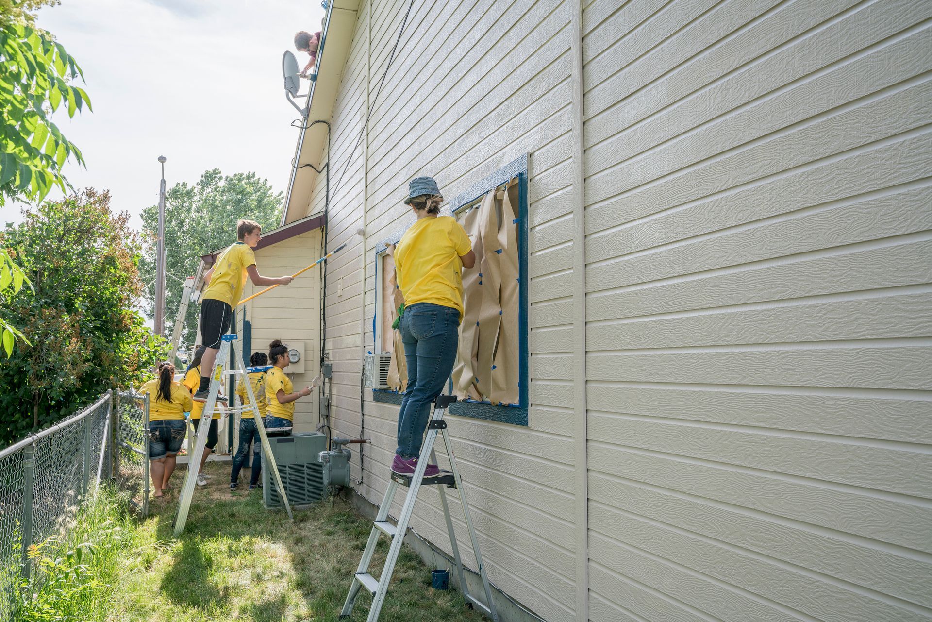 A group of people are painting the side of a house.