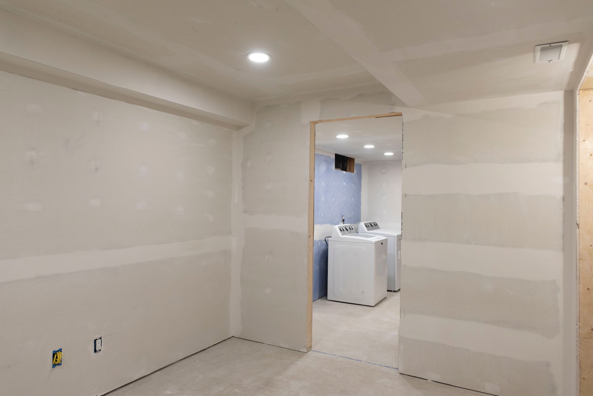 Room with drywall walls, doorway to laundry area, unfinished construction.