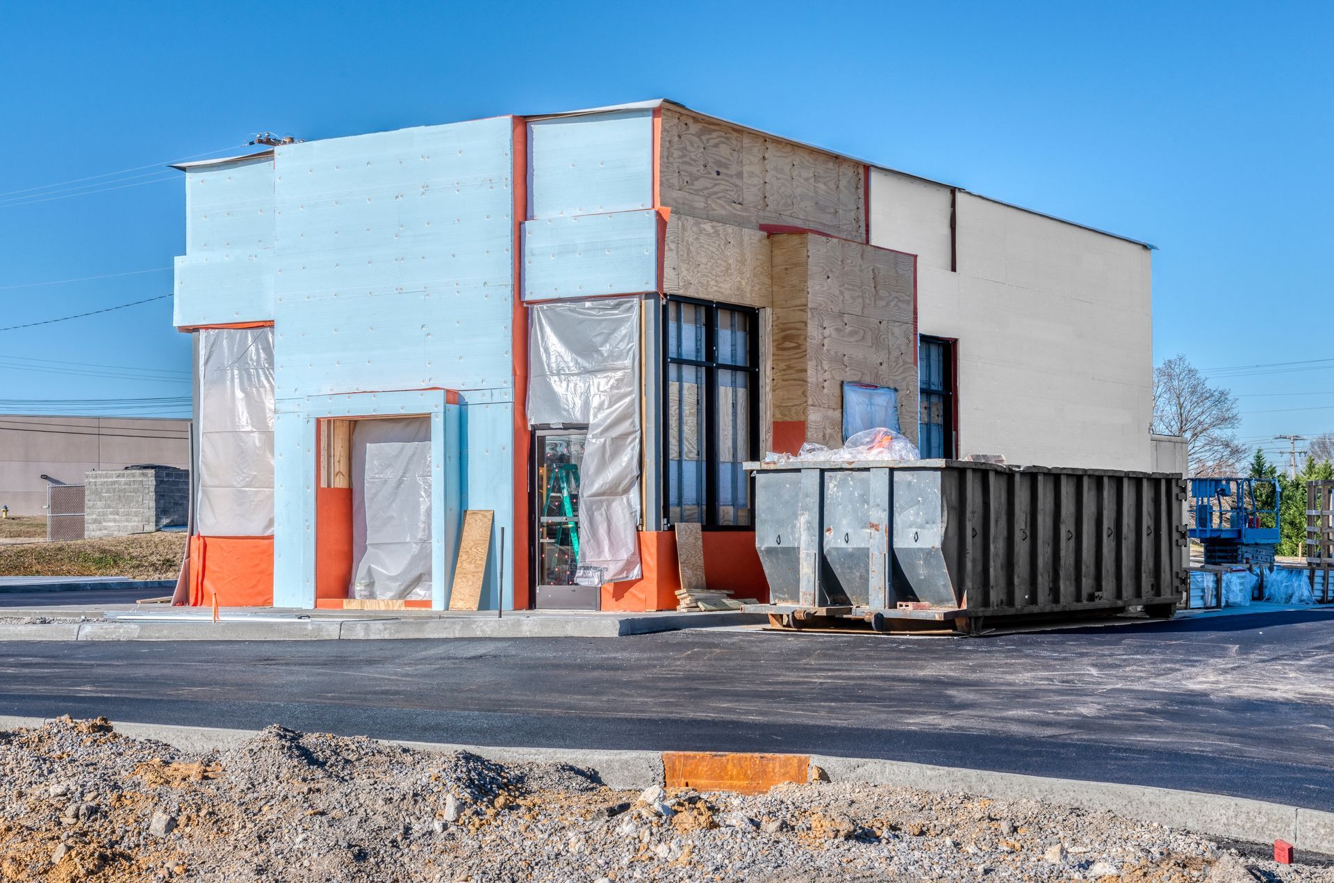 Building under construction with exposed walls and dumpster in front.