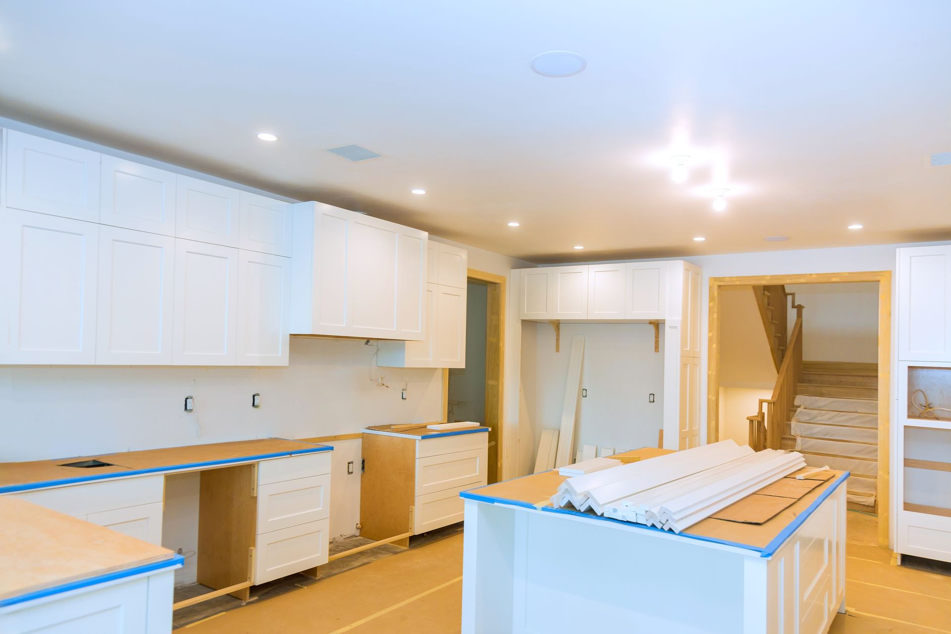 Kitchen under construction; white cabinets installed, island with trim, unfinished.