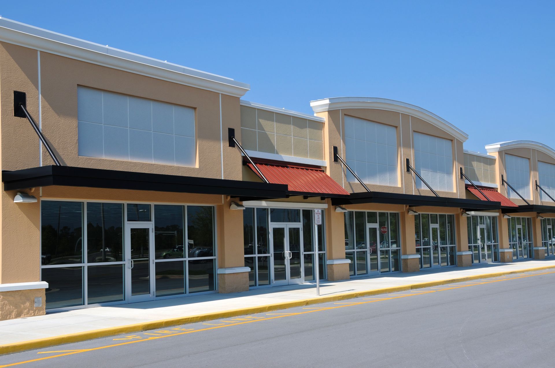 Row of empty storefronts with awnings under a clear blue sky.