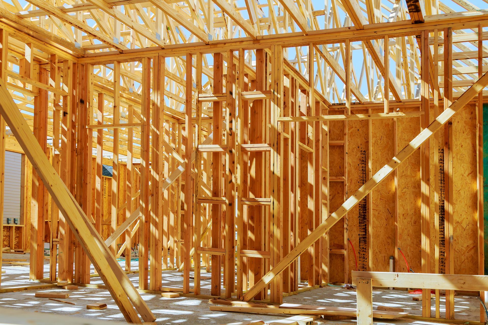 Wooden frame of a building under construction, sunlight streaming through.