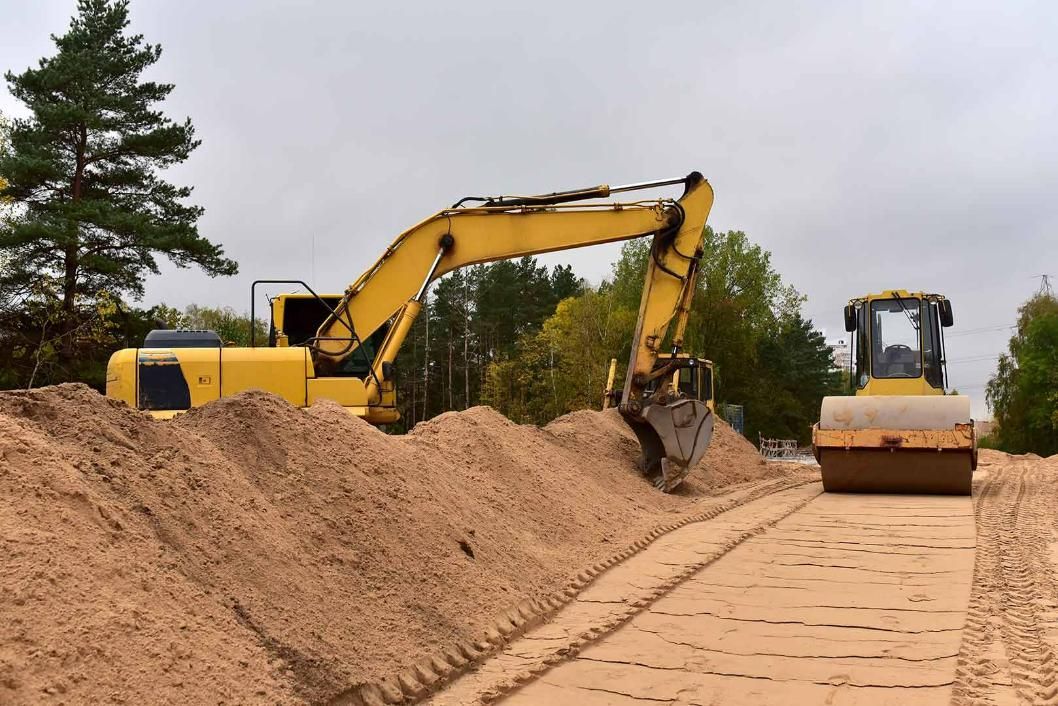 Two Construction Vehicles Are Working On A Dirt Road — Absolute Dingo Services in White Rock, QLD