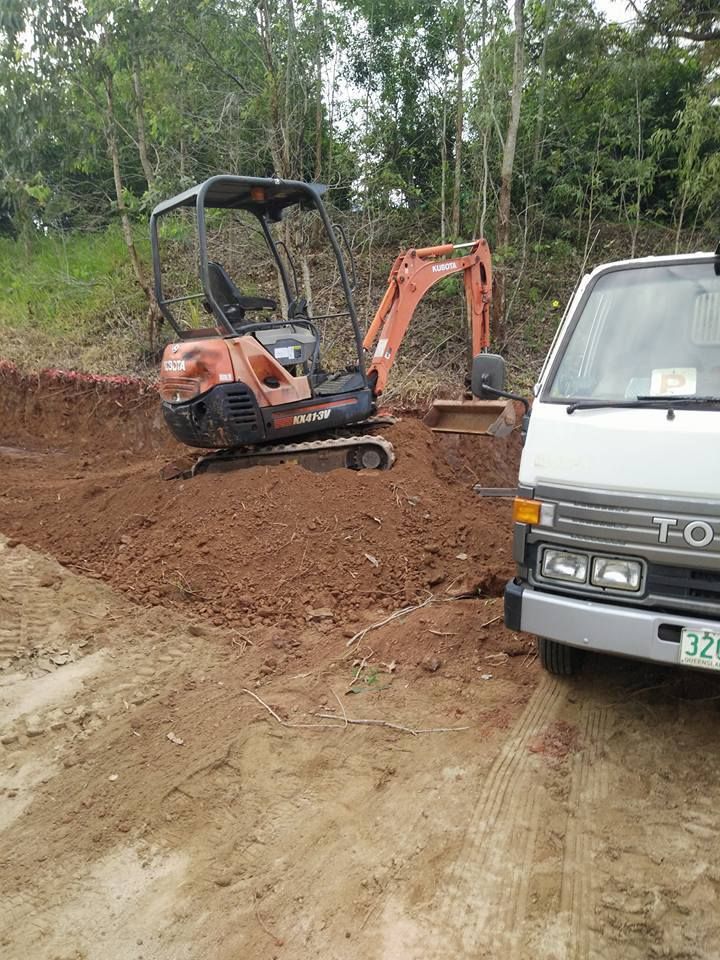 A White Truck Is Parked Next To A Small Excavator On A Dirt Road — Absolute Dingo Services in White Rock, QLD