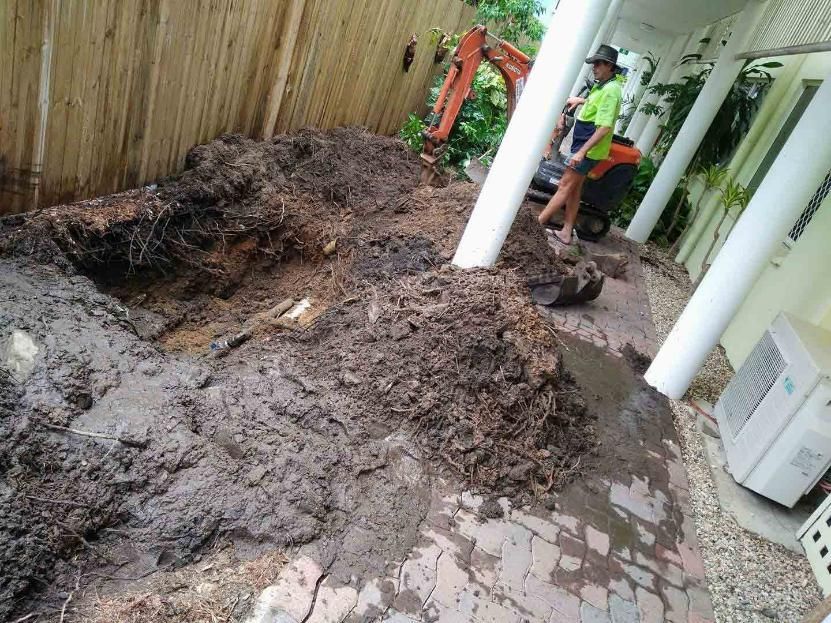 A Man Is Digging A Hole In The Dirt In Front Of A House — Absolute Dingo Services in White Rock, QLD