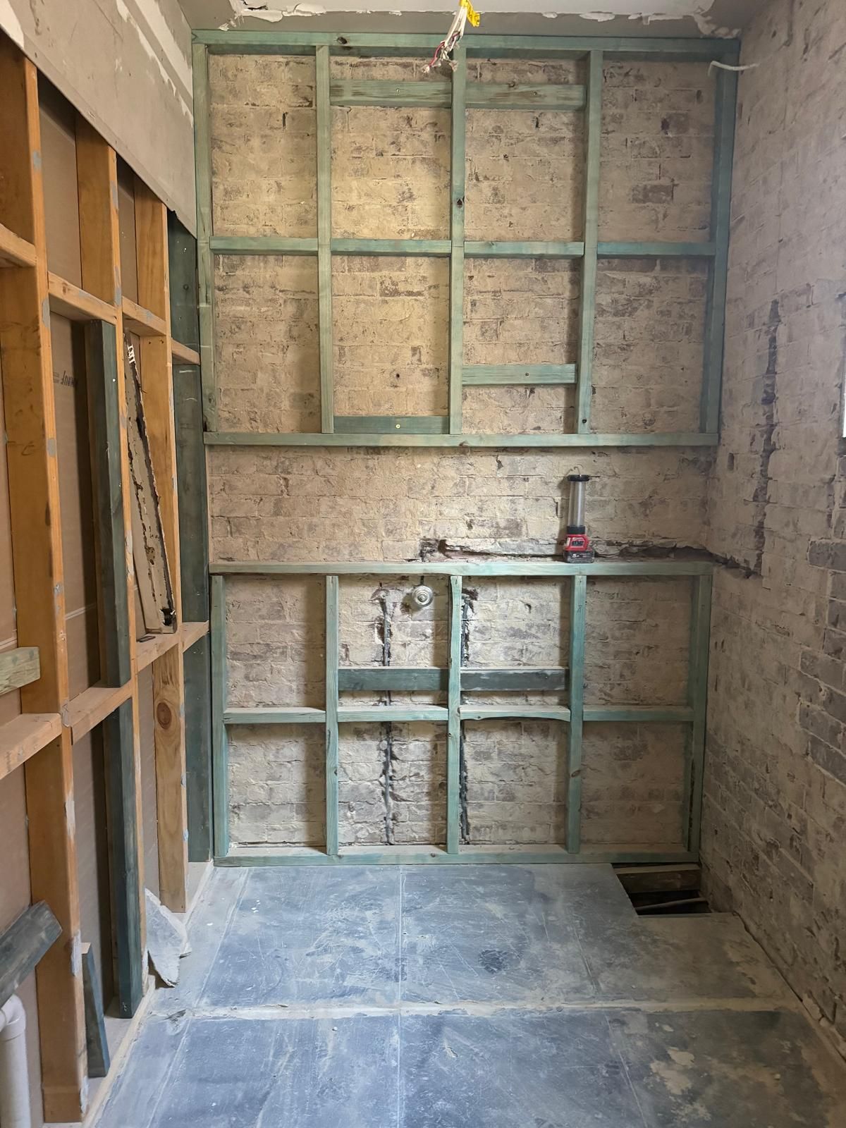 Bathroom renovation in progress, framing on brick walls.