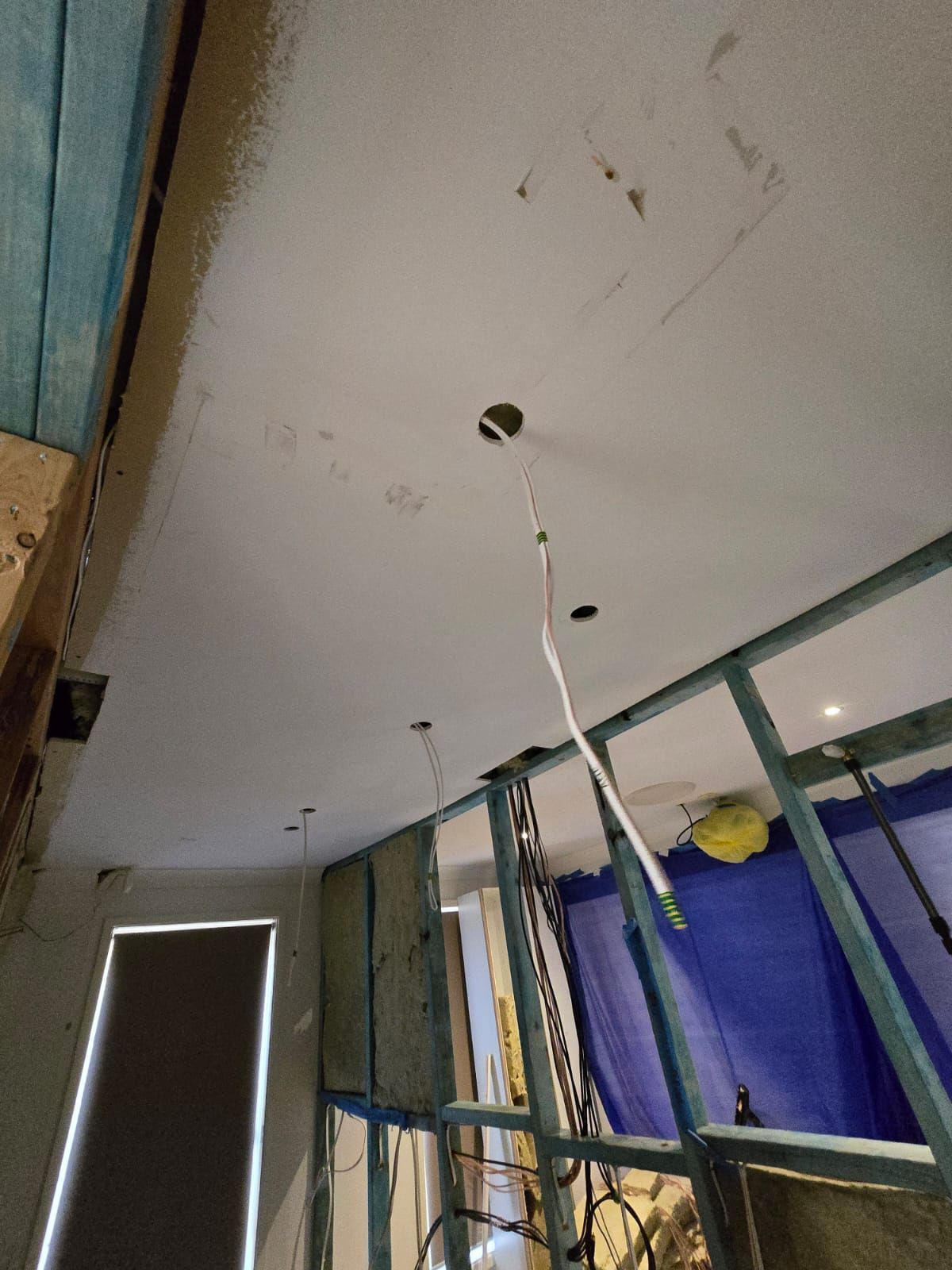 Construction interior: ceiling with exposed wiring, metal framing, unfinished walls, and dark shade.