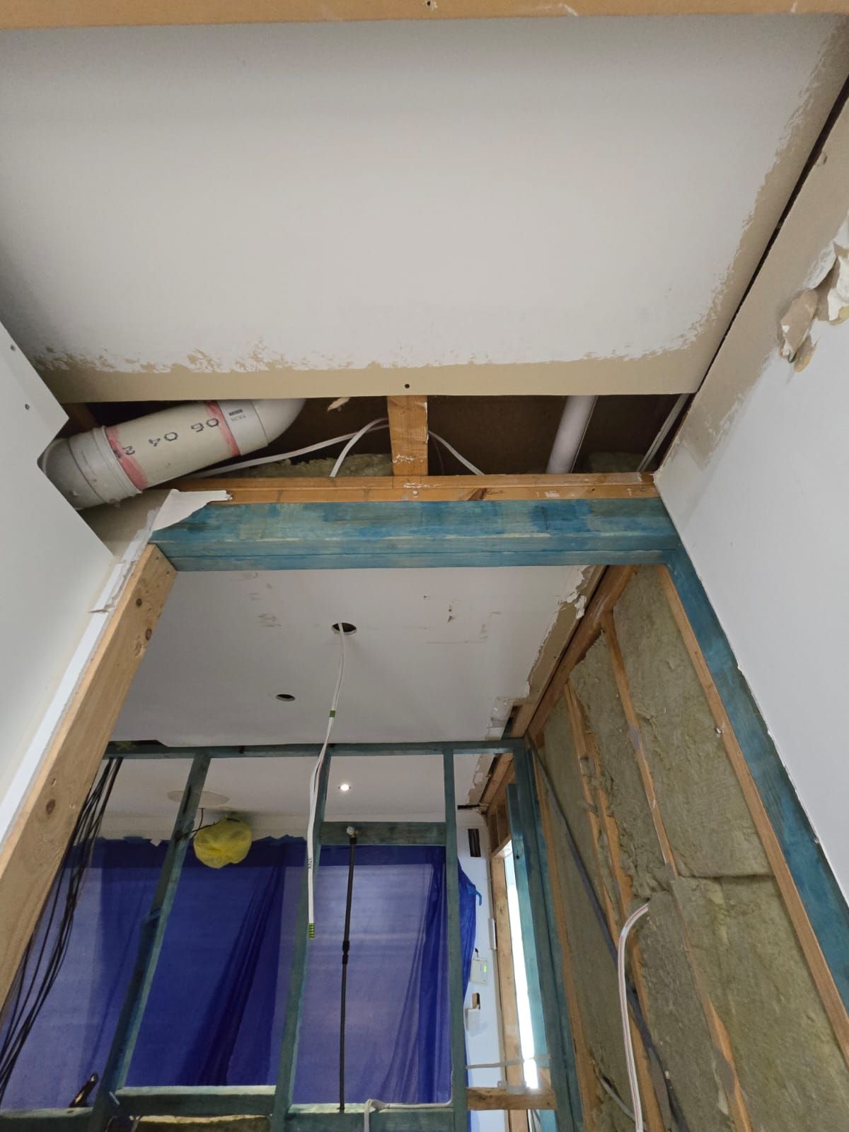 Construction site: doorway with exposed framing, plumbing, and insulation.