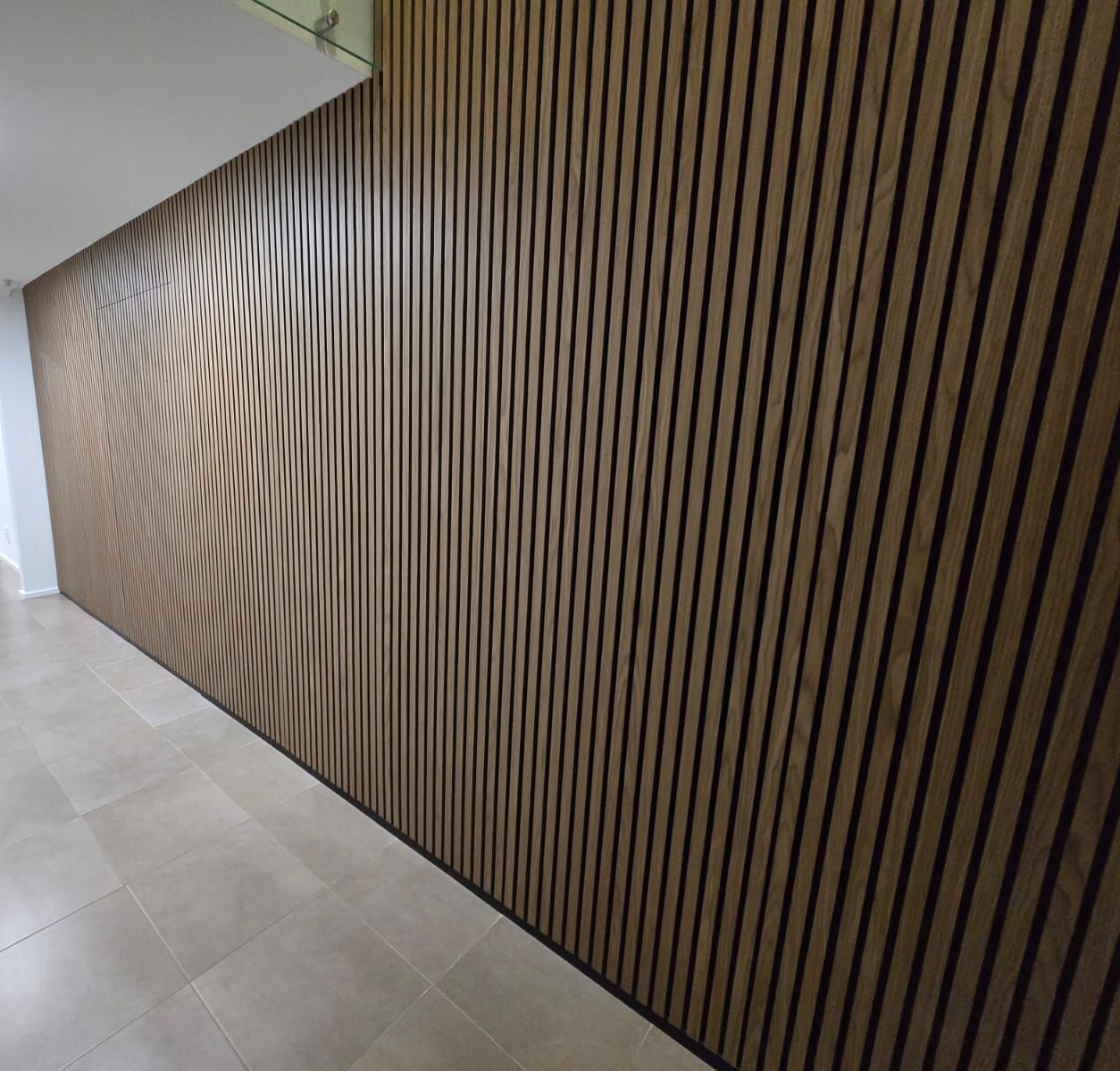 Wood panel wall with wave pattern on the left side, vertical lines on the right. Beige tiled floor.