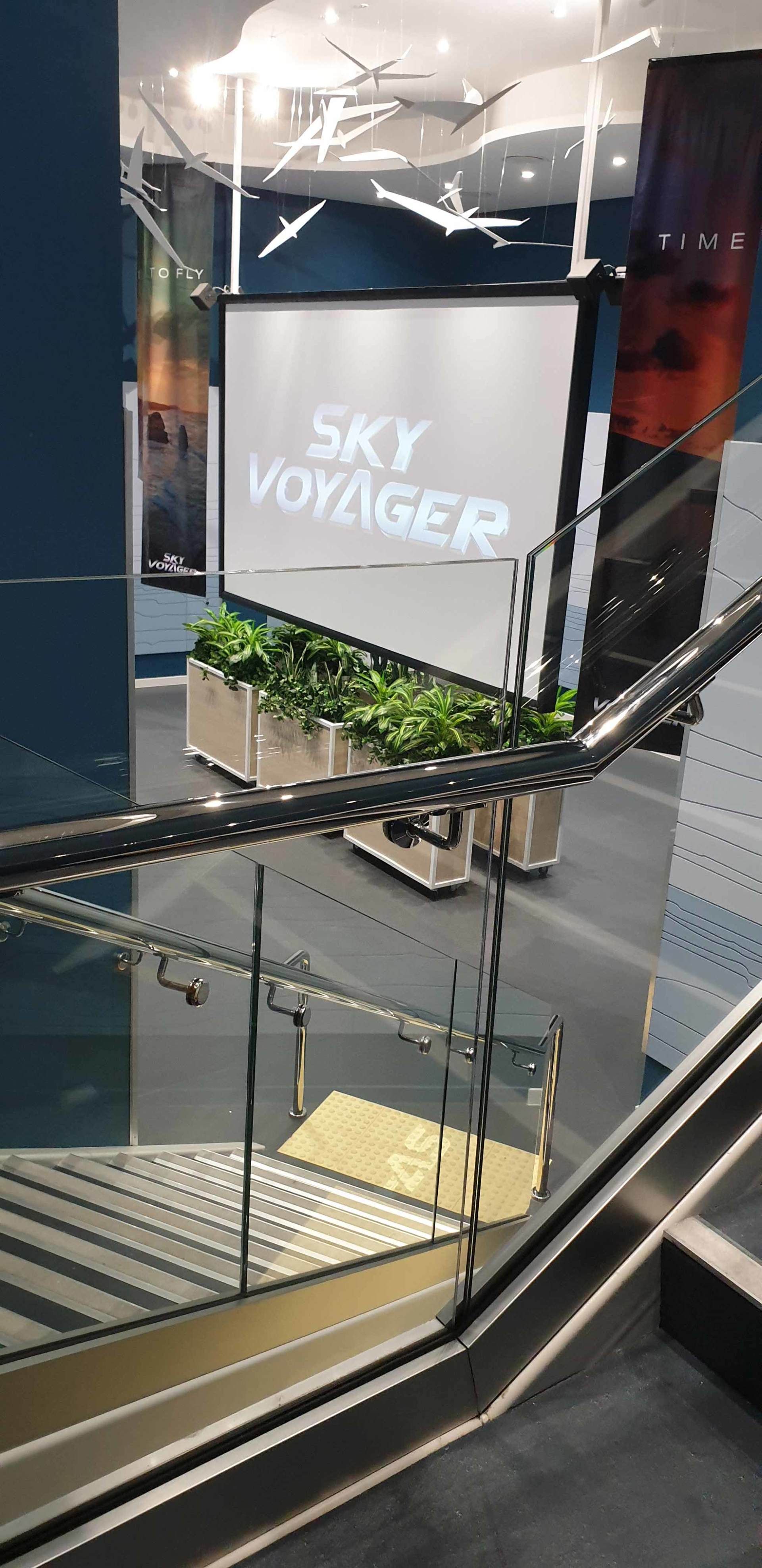 A view of an interior with escalators, the words 