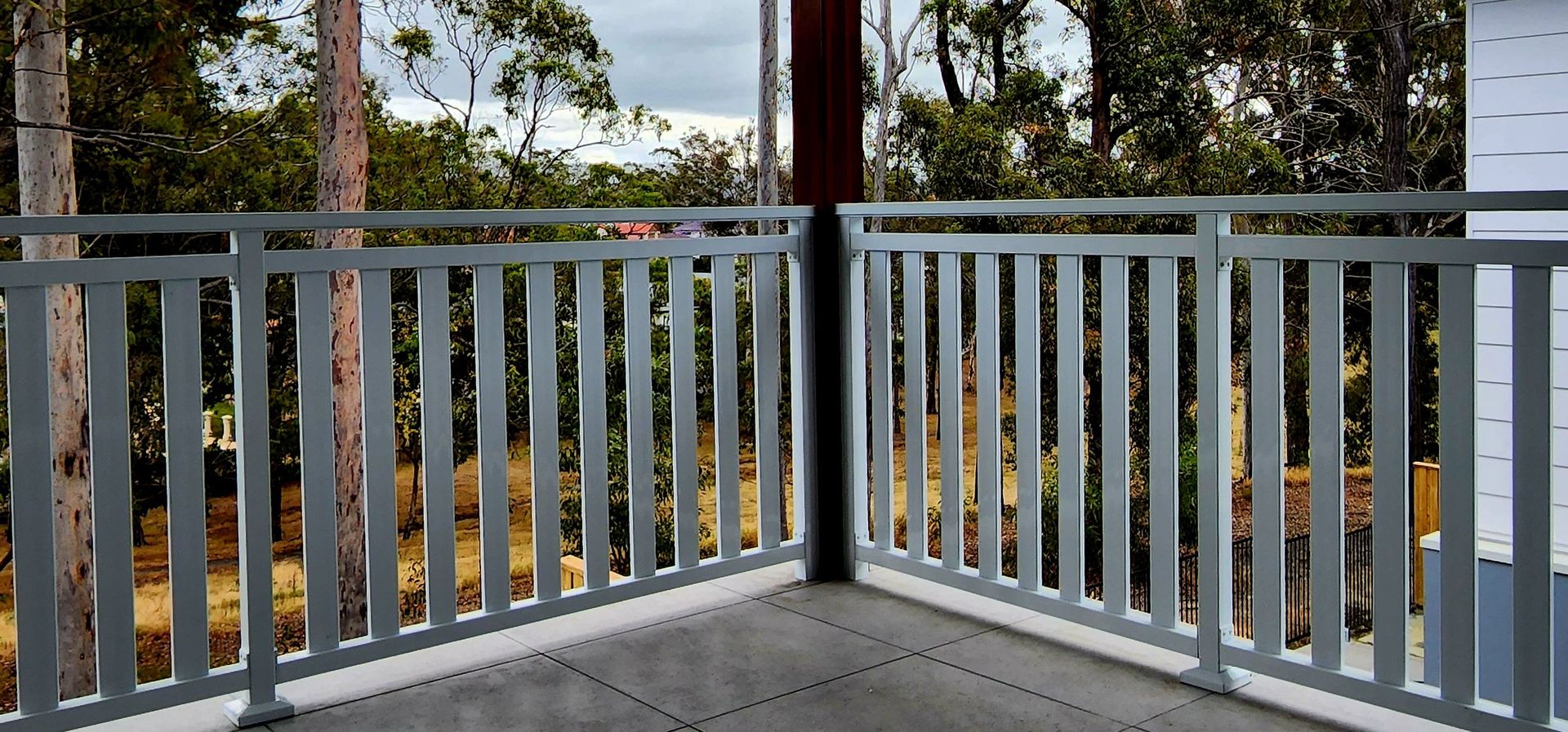 Gray metal railing on a balcony overlooking trees.