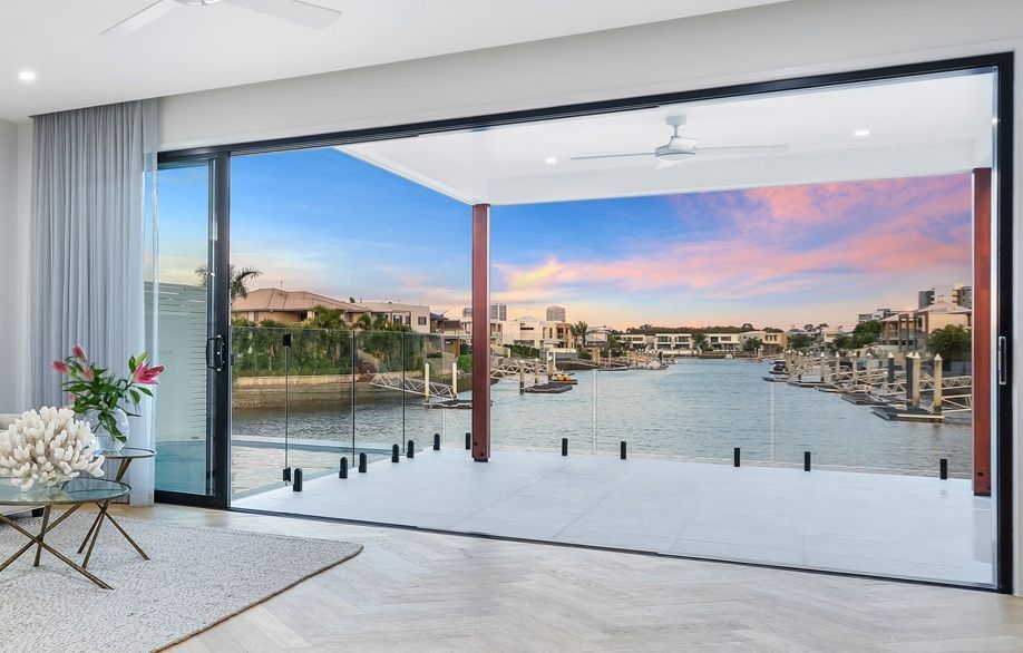 Open sliding glass doors overlooking a waterfront with boats. Pink and blue sunset.