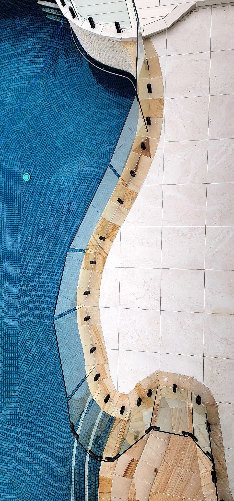 Pool with blue water, curved beige trim, and white tile surround.