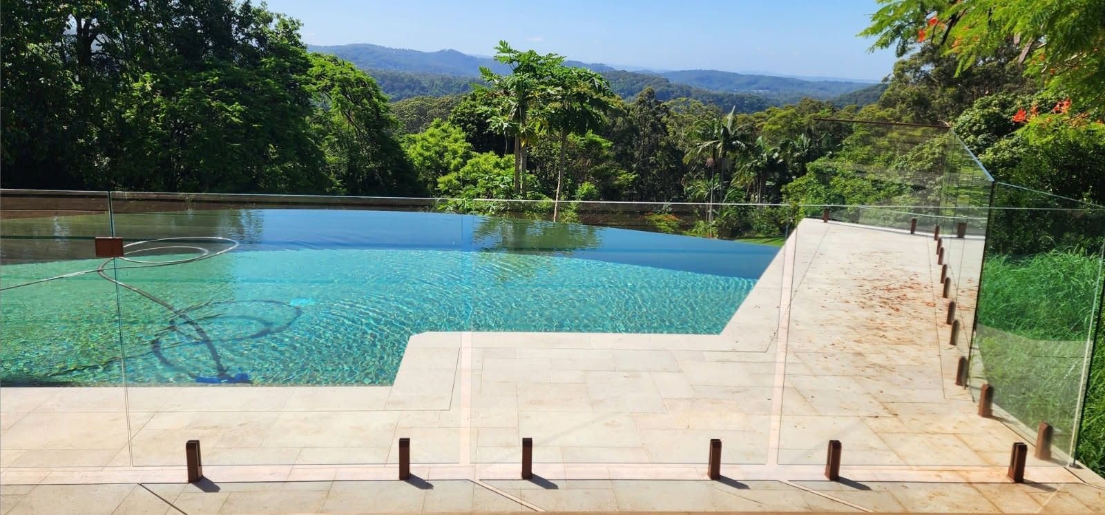 An infinity pool with a scenic view of lush green trees and mountains.